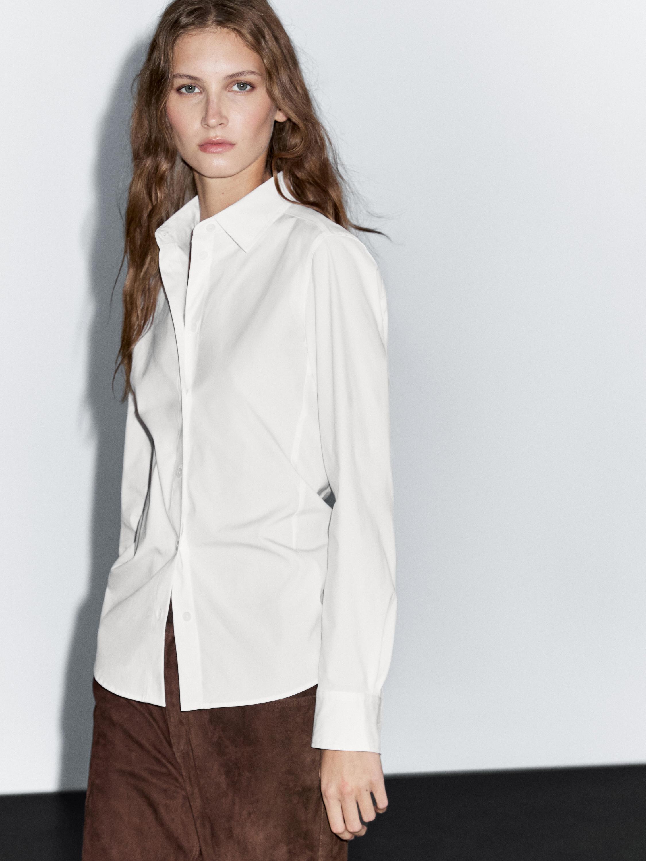 Completo di camicia bianca a maniche lunghe con colletto classico e gonna marrone.