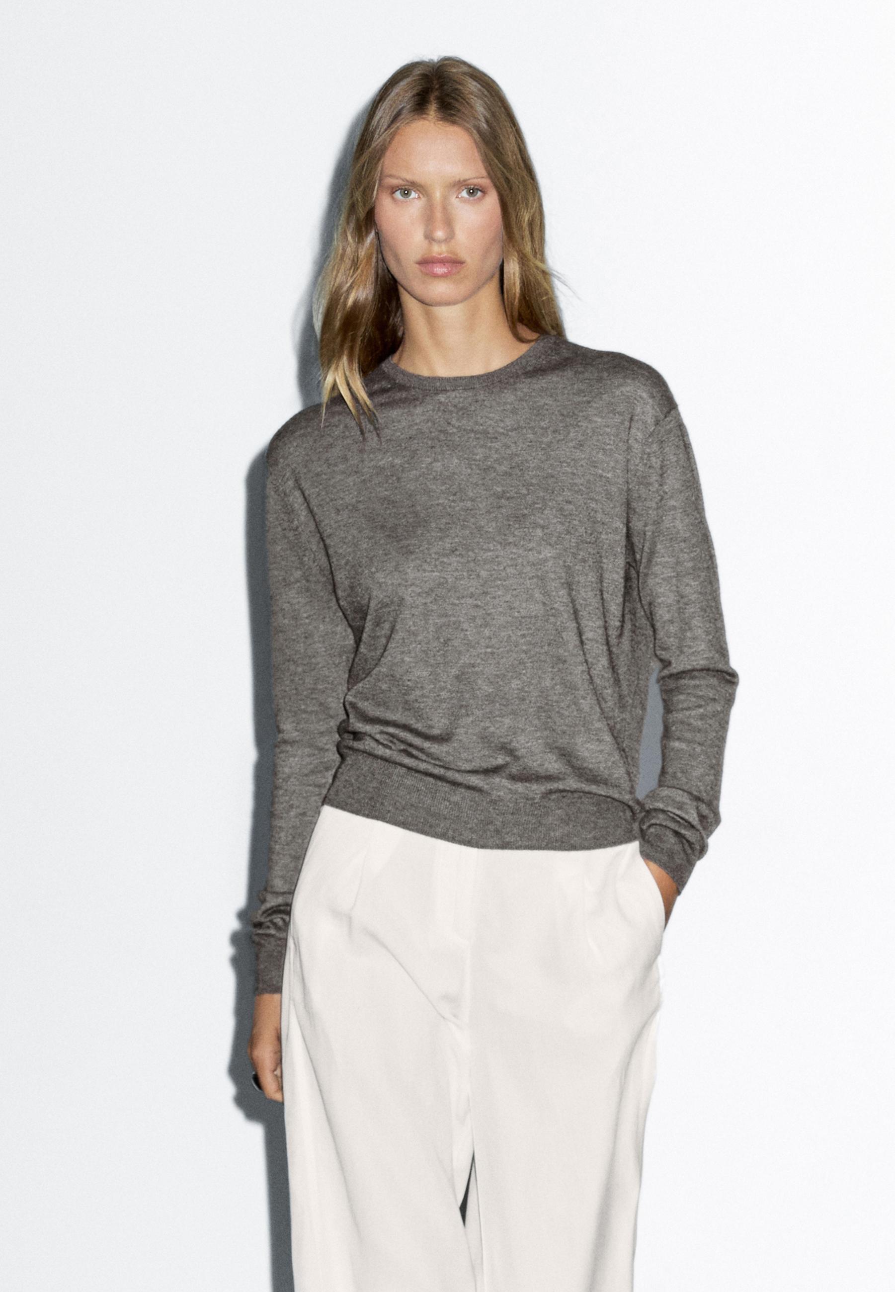 طقم بلوفر رمادي محبوك بياقة دائرية وبنطلون كريمي.