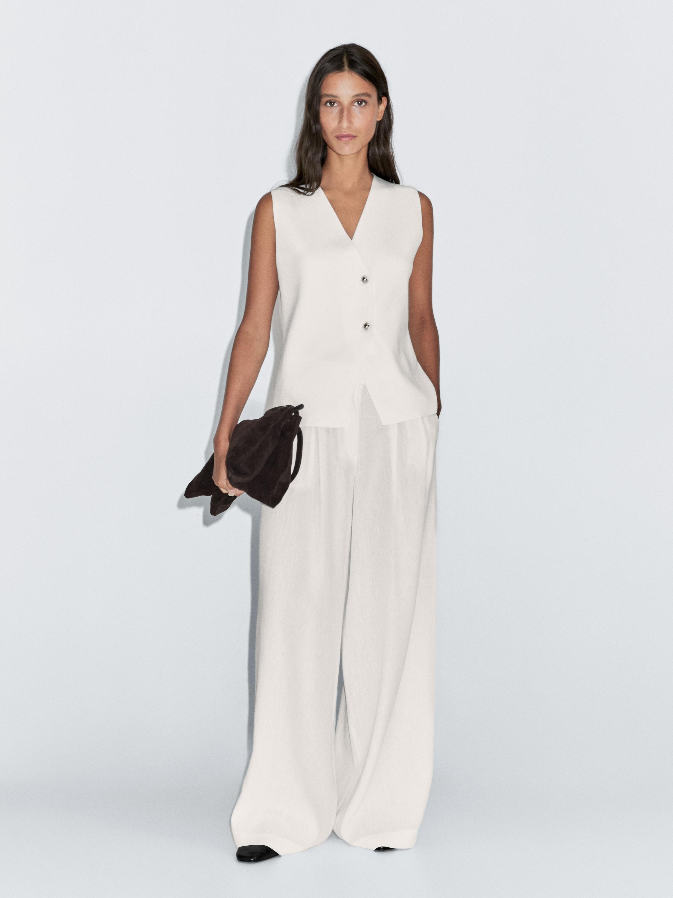 Conjunto de chaleco blanco hueso con cuello en V y botones, pantalones anchos a juego.