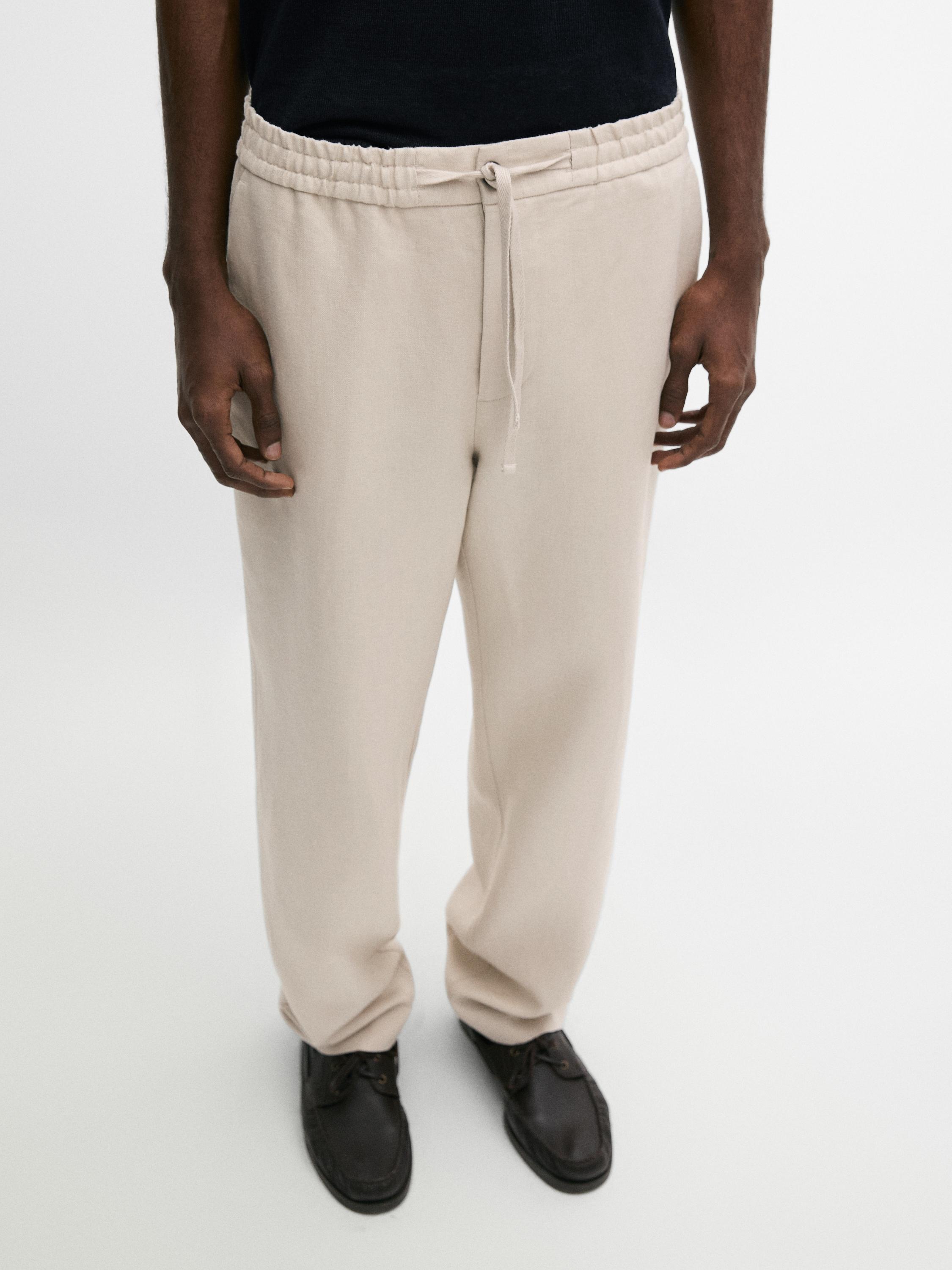 Plano medio de pantalones beige con cintura elástica y cordón ajustable.