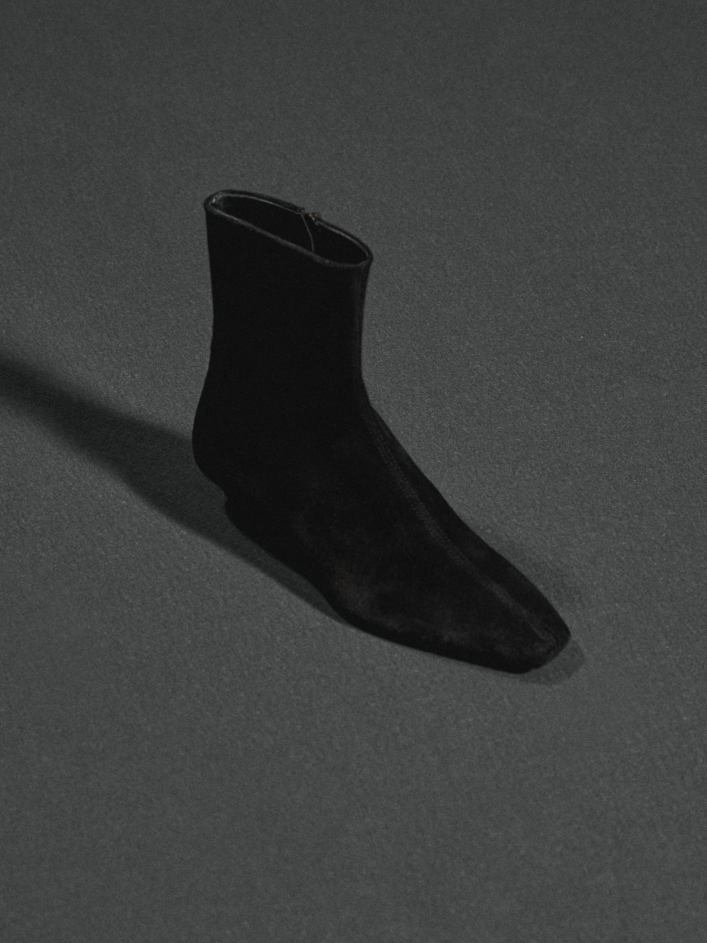 Vista lateral de botín negro con punta afilada y cierre lateral.