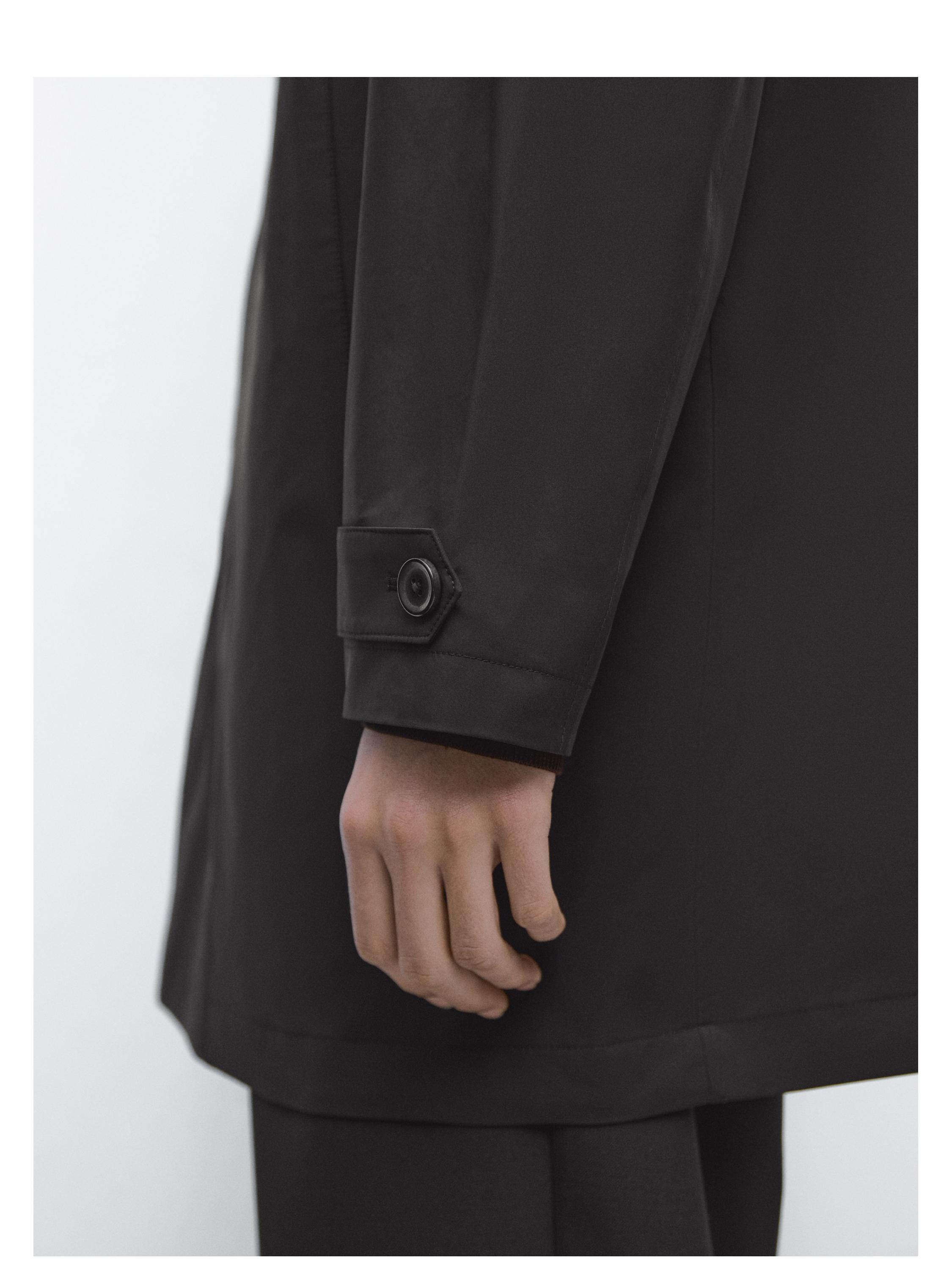 لقطة متوسطة لكم سترة باركا سوداء مع سوار معصم قابل للتعديل وزر ظاهر.