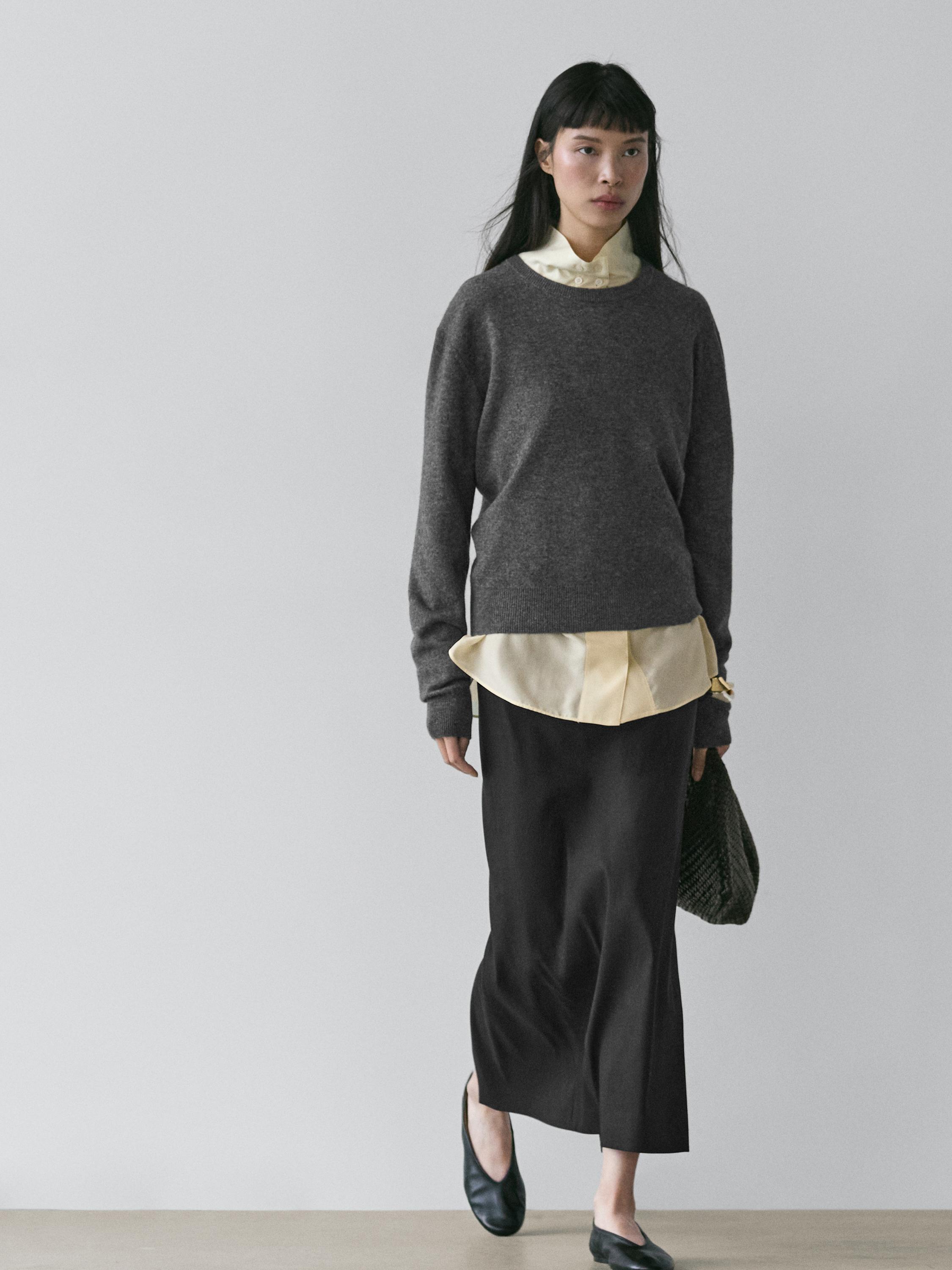 Conjunto de falda midi negra recta, suéter gris y camisa beige visible en el cuello y bajo.