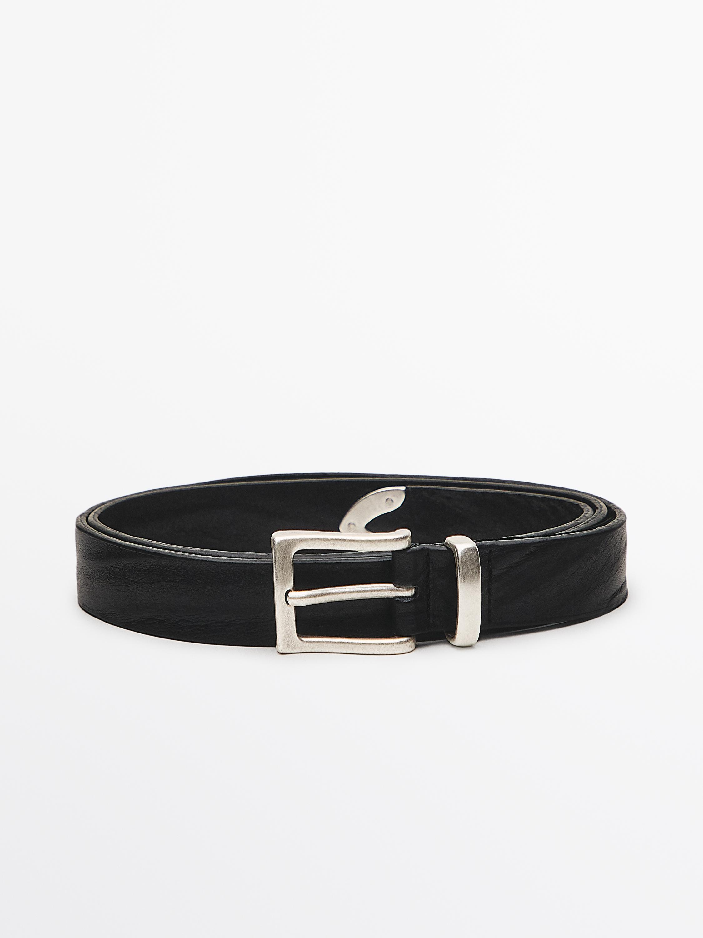 Ceinture noire avec boucle métallique rectangulaire et détail de bout.