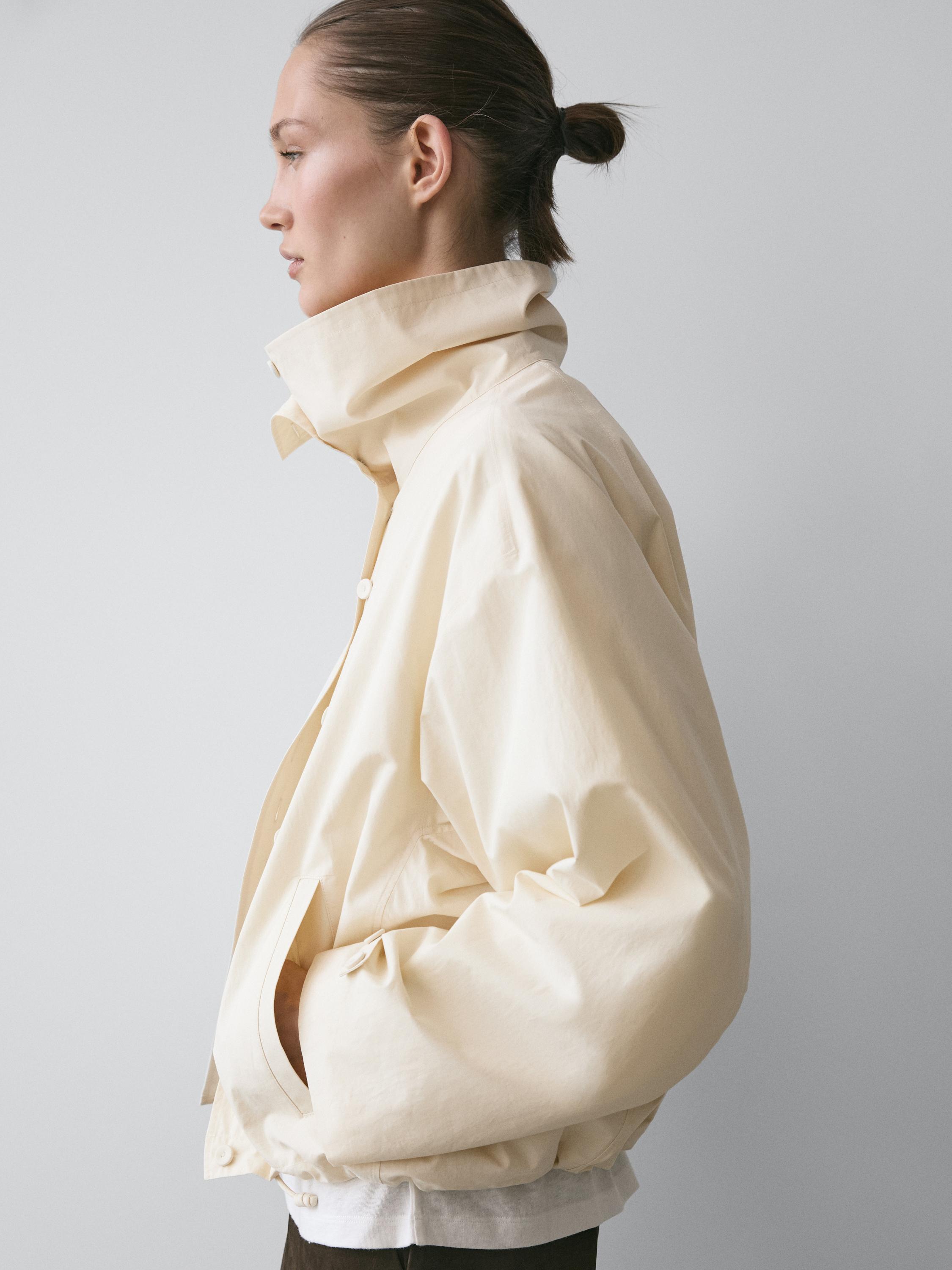 Mid-shot of a raw jacket with a high collar and side pockets. Visible buttons detail at the bottom.