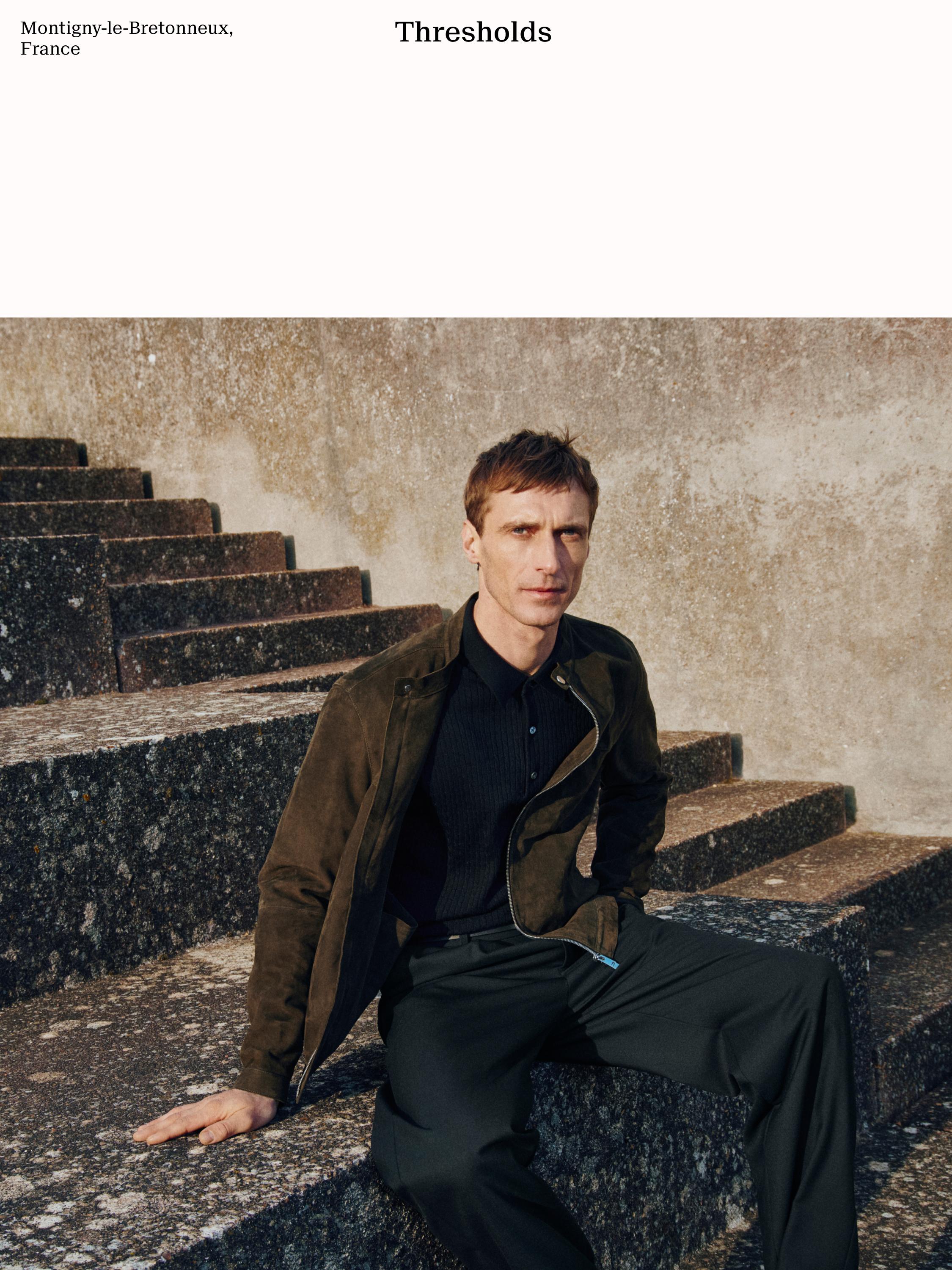 Conjunto de chaqueta marrón, camisa negra de cuello y pantalones negros. Texto visible: "Montigny-le-Bretonneux, France", "Thresholds".