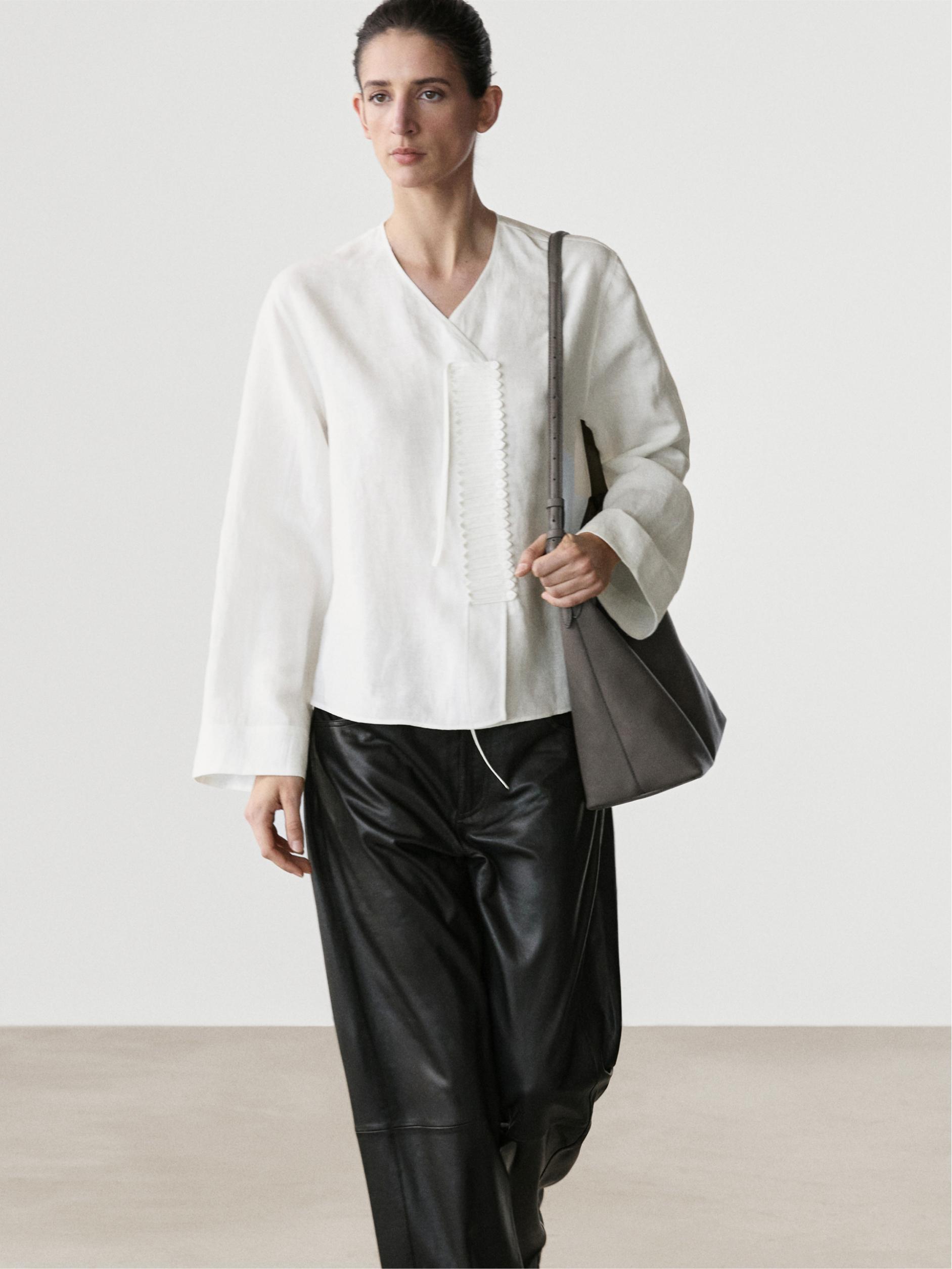 Conjunto de camisa blanca fluida con detalle de pechera y pantalones negros amplios.