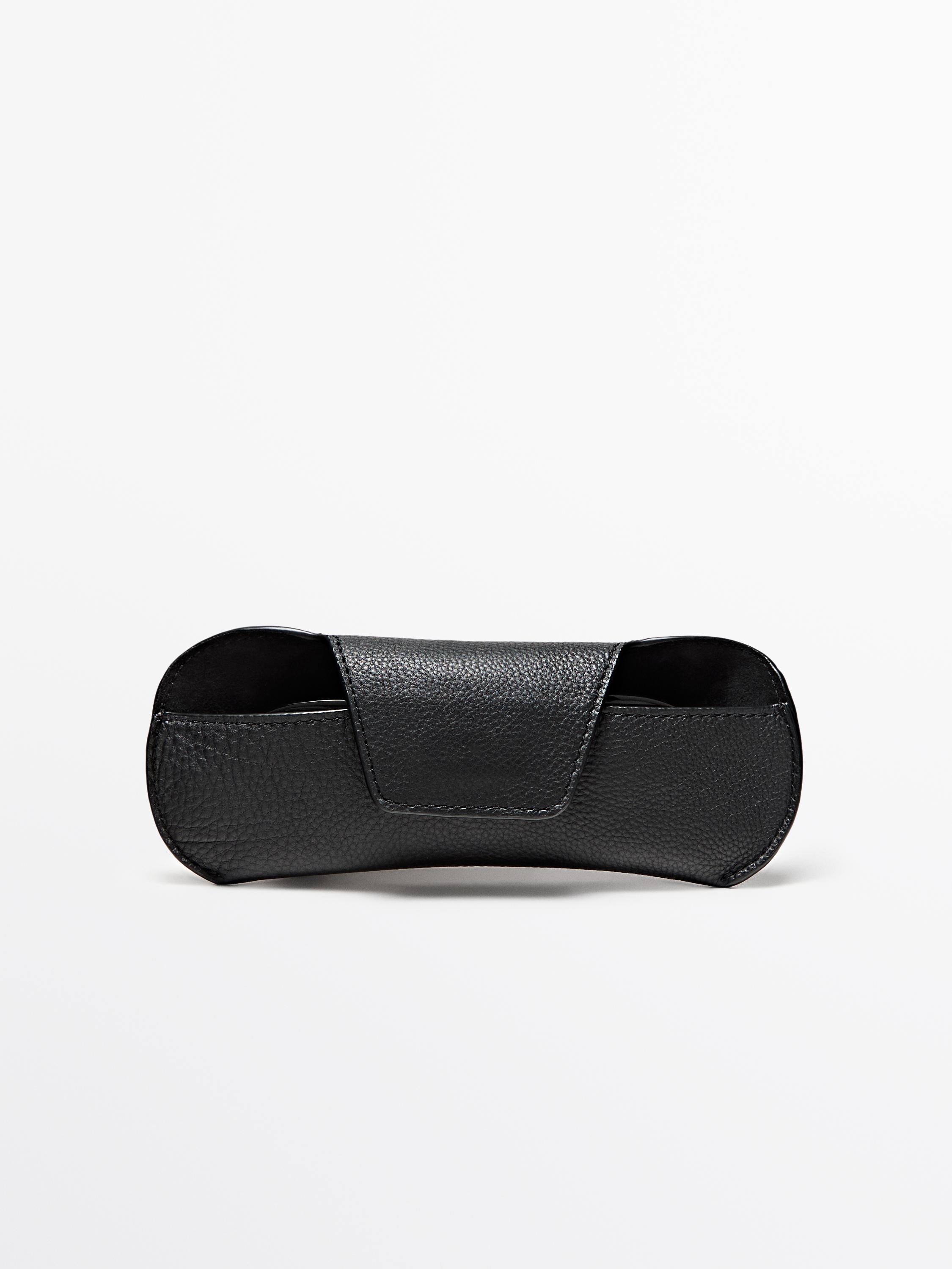 Front view of a black glasses case with a flap and a grainy texture.