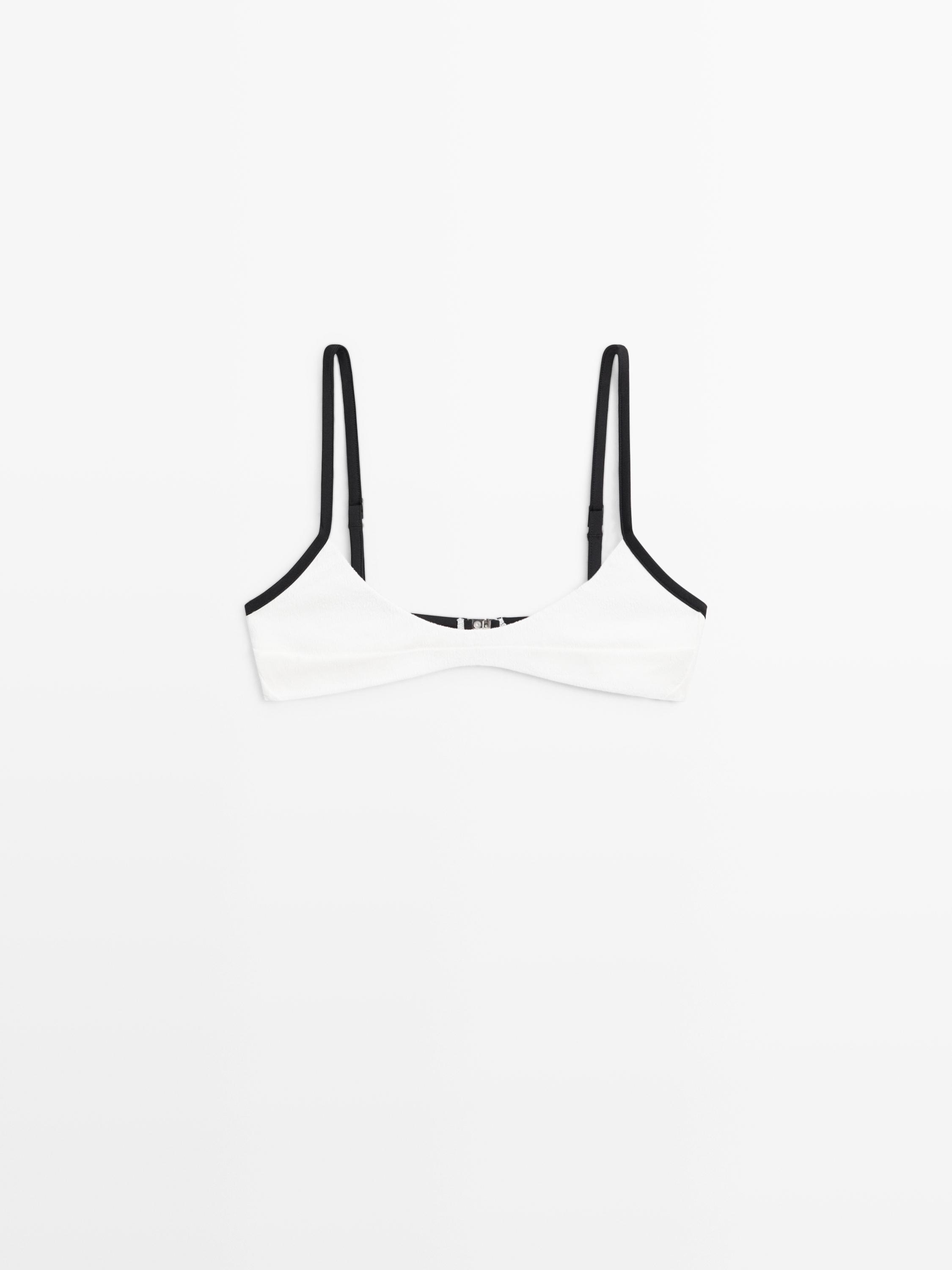 Vista frontal de top de bikini blanco roto con tirantes finos negros y borde negro en el escote.