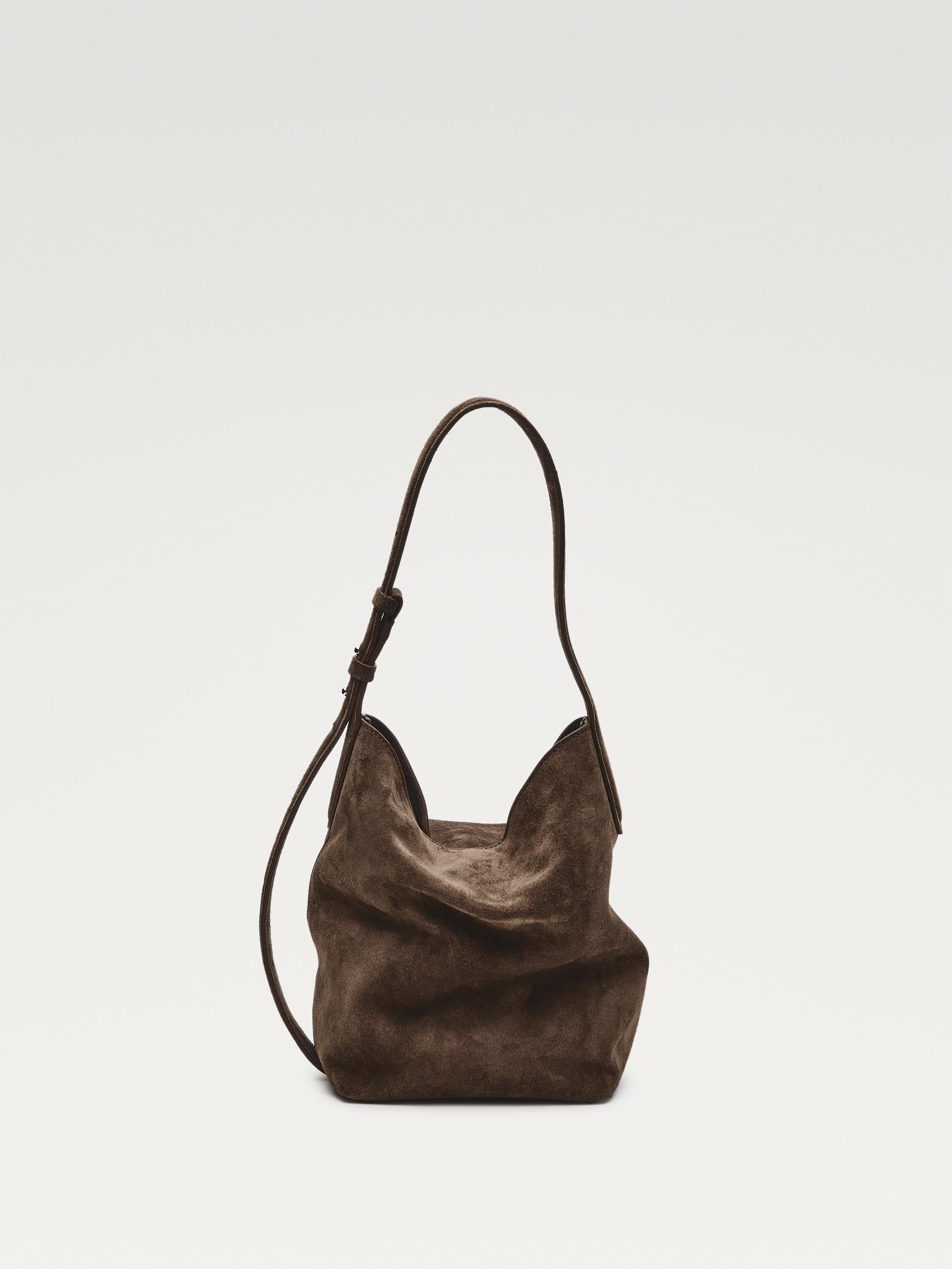 Front view of a taupe brown handbag with an adjustable strap and a soft, structured design.