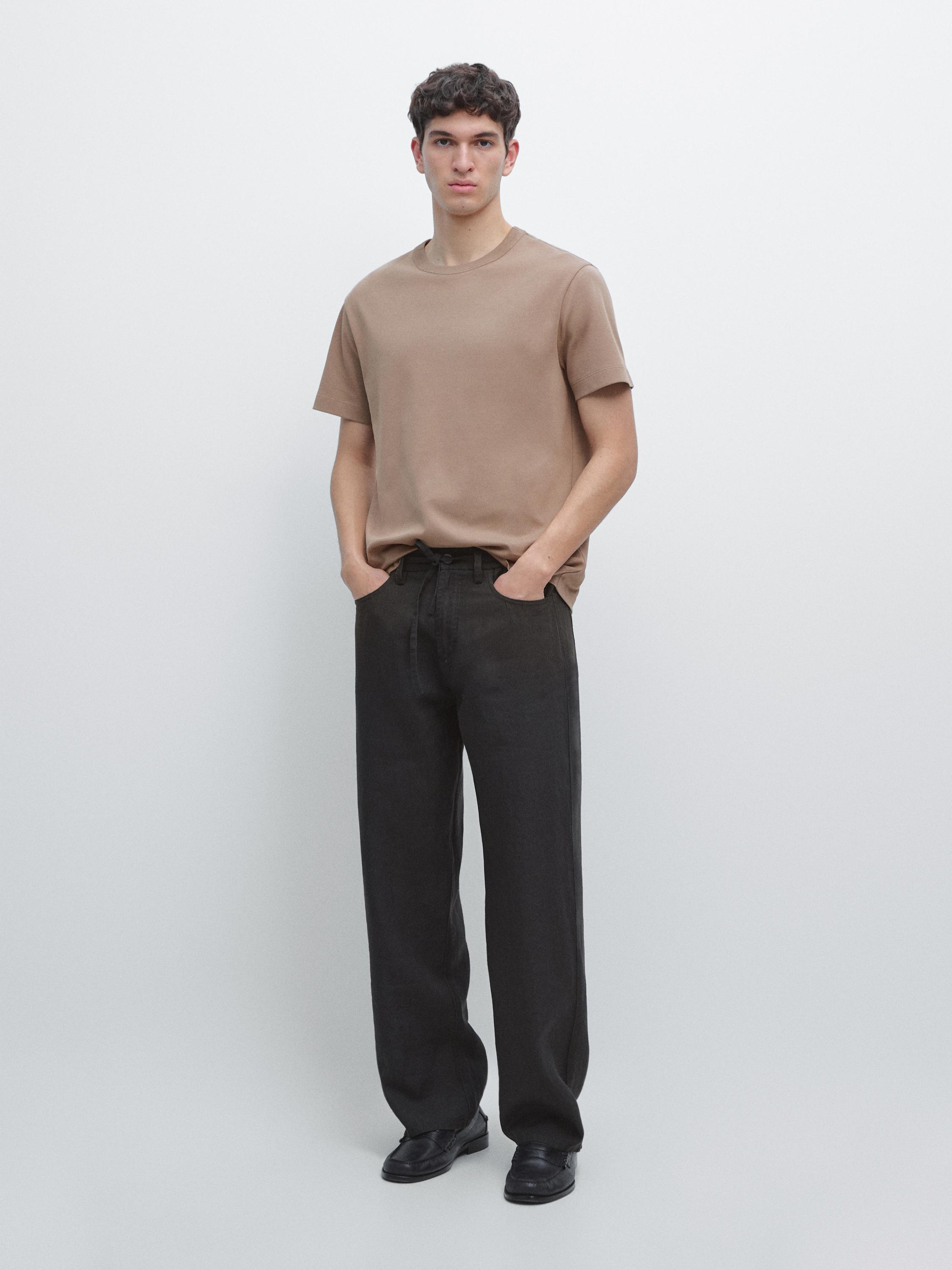 Conjunto de playera café de manga corta y pantalones oscuros de corte recto.