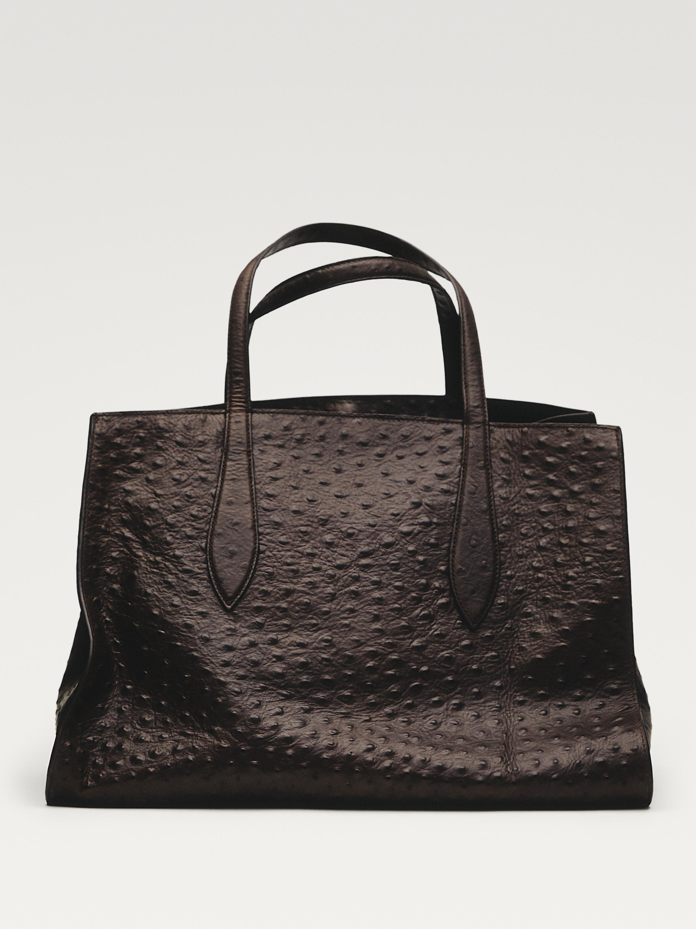 Vista frontal de bolso marrón con textura de puntos y asas dobles.