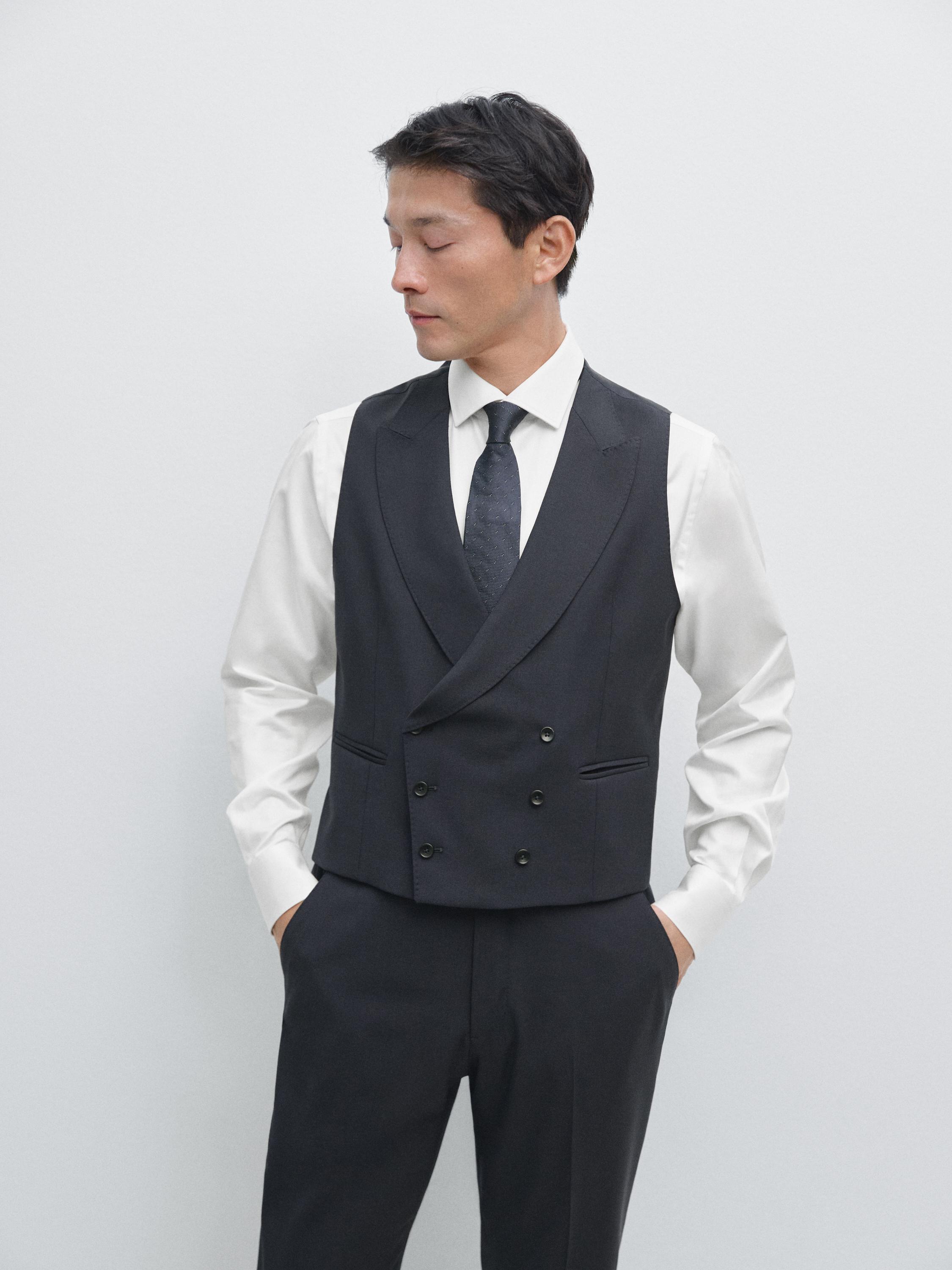 Σετ ναυτικού μπλε γιλέκο με διπλό κούμπωμα και πλαϊνές τσέπες, λευκό πουκάμισο και μαύρη γραβάτα.