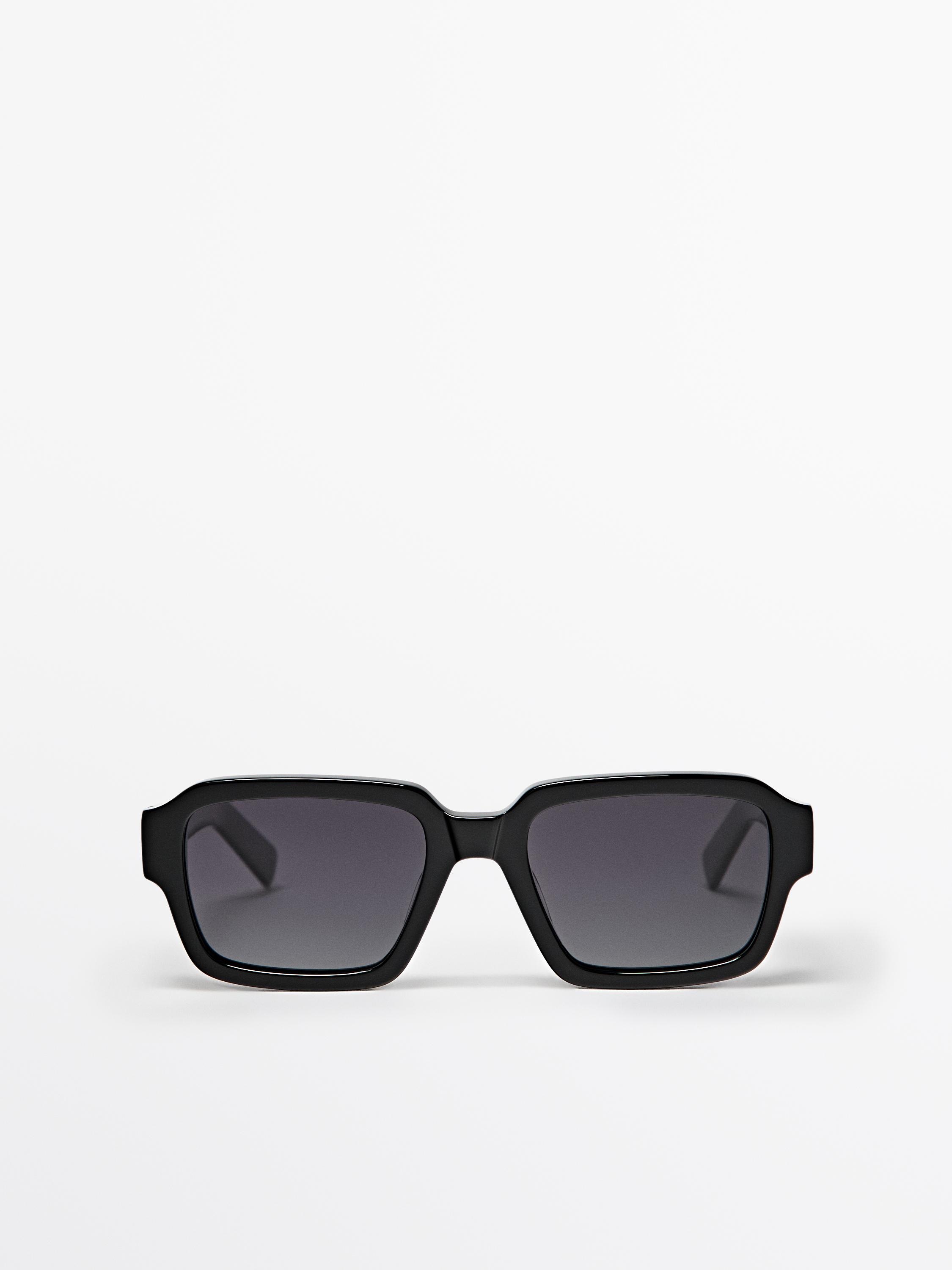 Lunettes de soleil noires avec monture rectangulaire et verres foncés.
