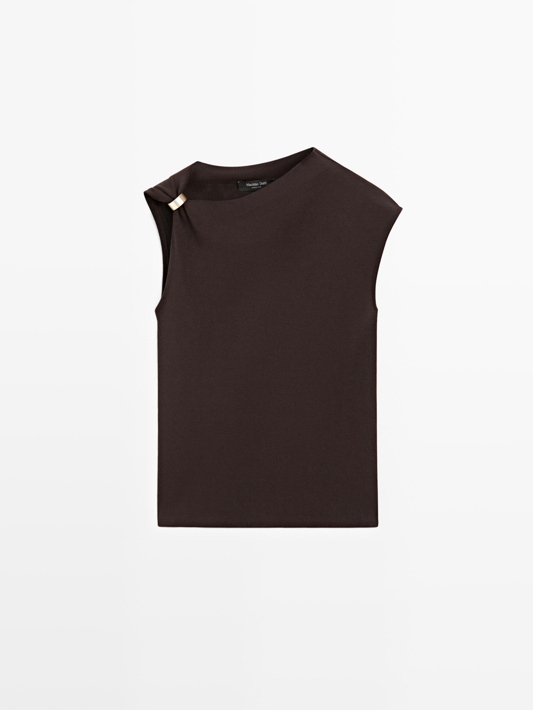 Front view of an asymmetrical brown sleeveless top with a brooch detail on the left shoulder.