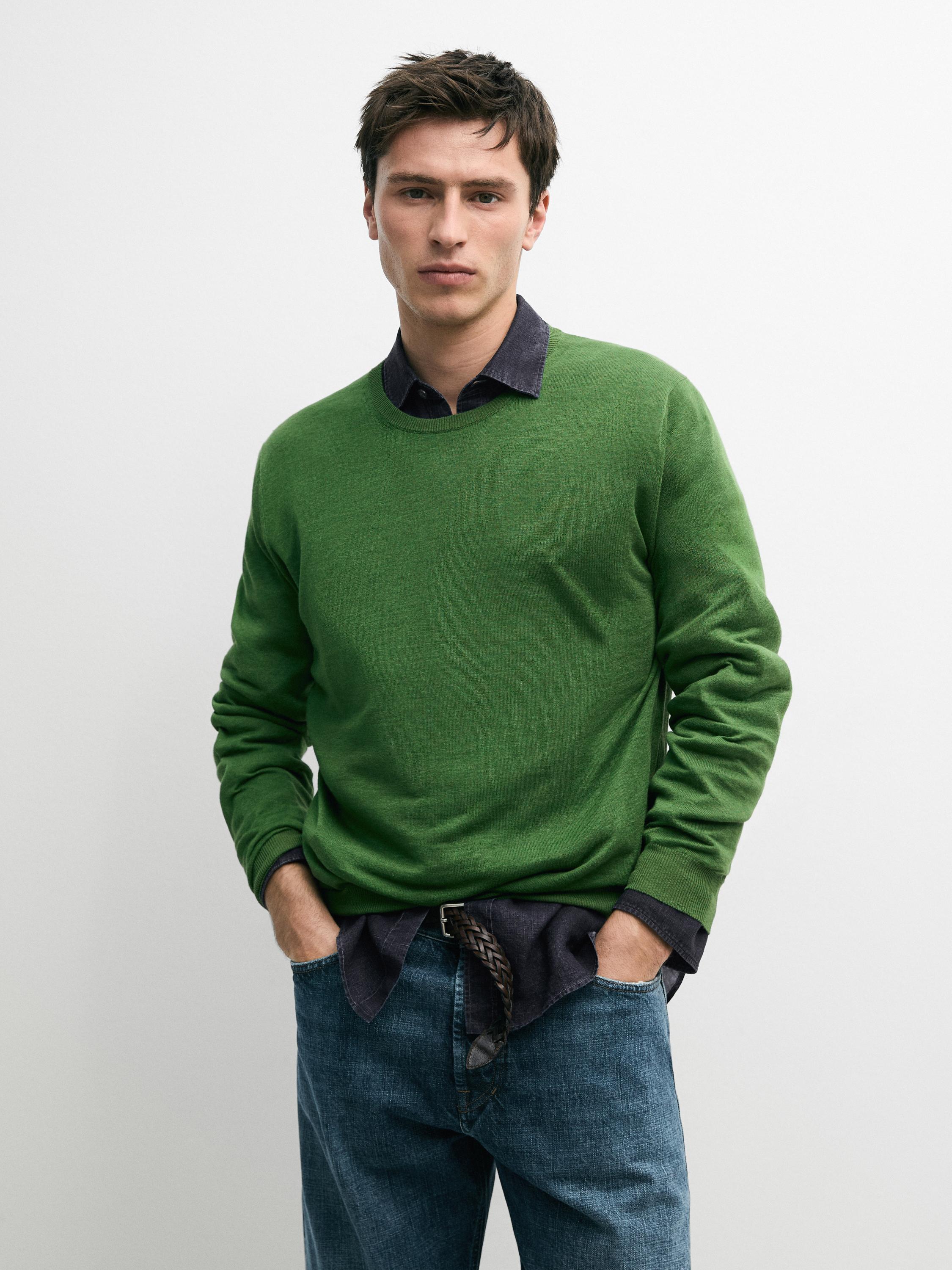 Conjunt de jersei verd llima de coll rodó sobre camisa fosca, combinat amb texans blaus.
