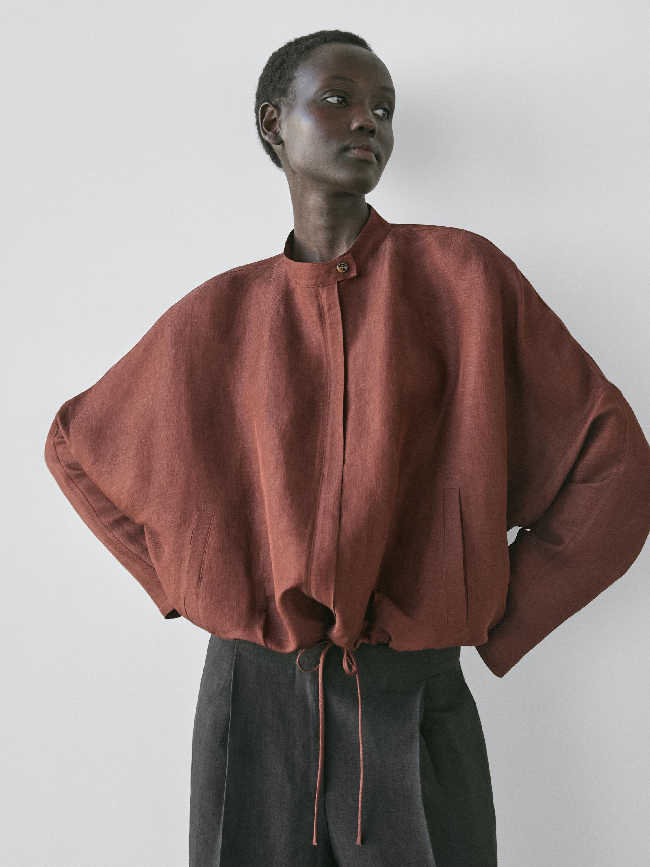 صورة متوسطة لجاكيت بومبر بني بياقة ماندرين، إغلاق بأزرار ورباط شد قابل للتعديل عند الخصر.