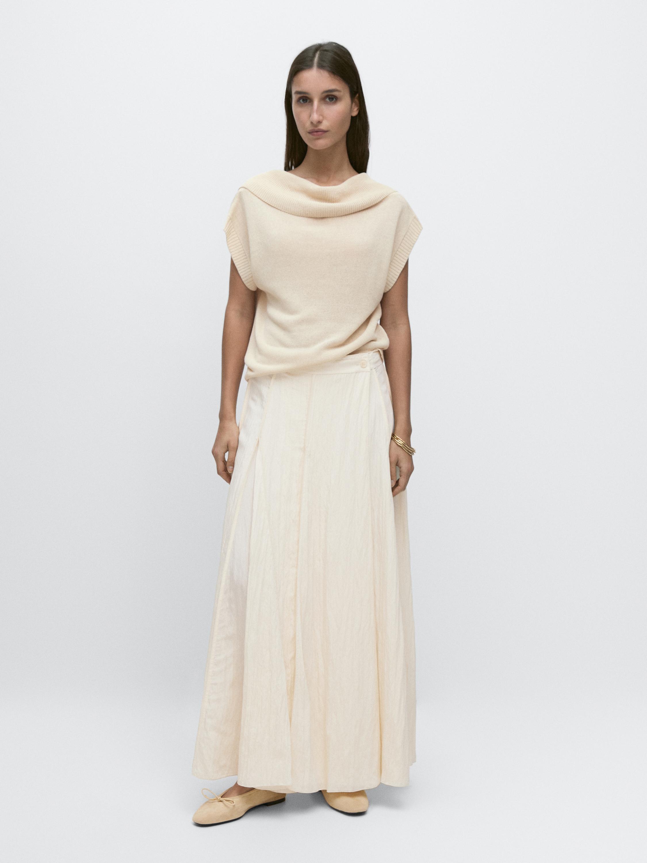 Beige sleeveless blouse with a draped neckline and a beige midi skirt with a sash detail.