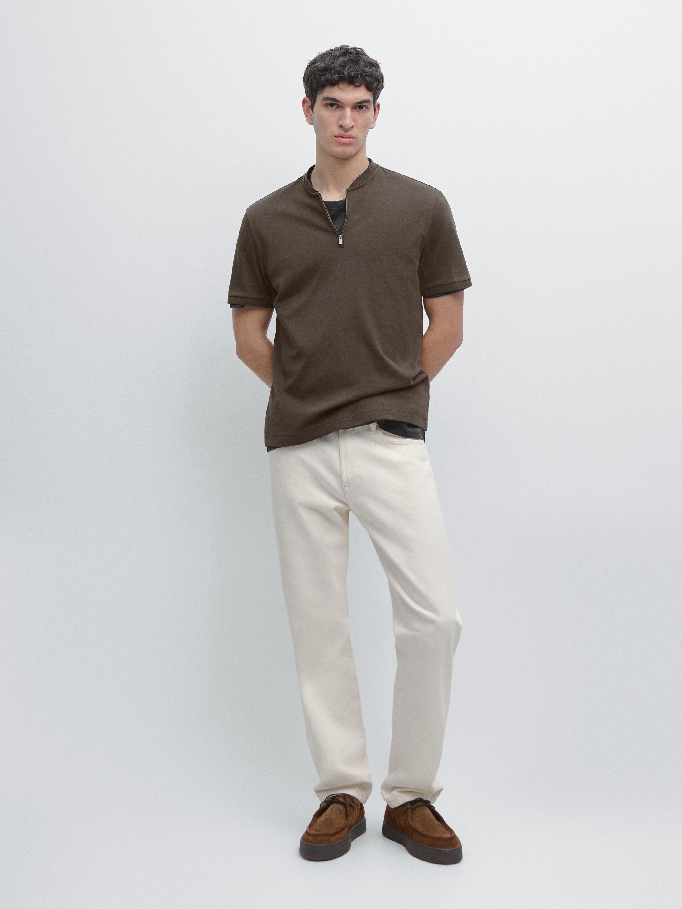 Conjunto de polo chocolate con cremallera y pantalones claros.