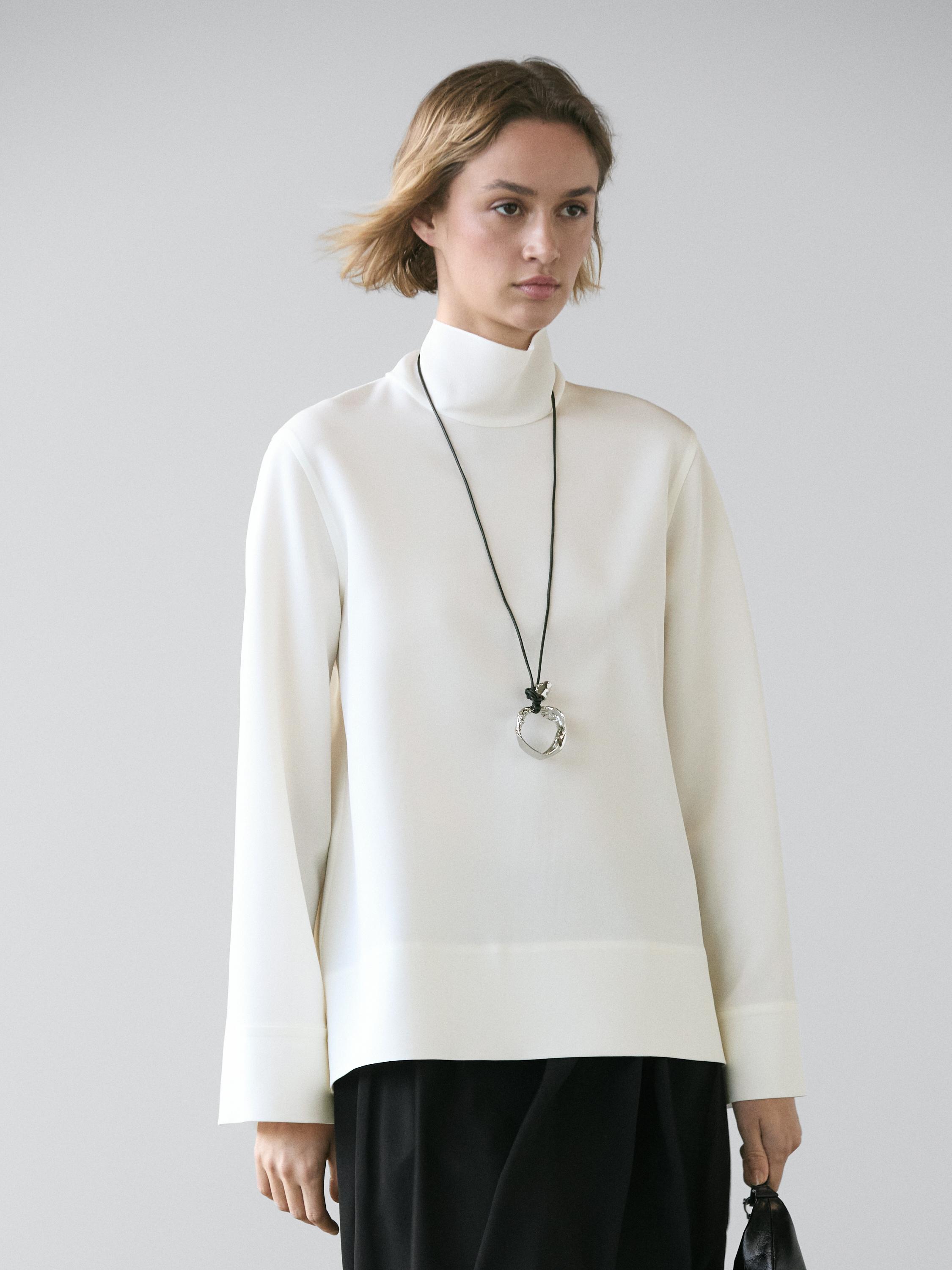 بلوزة بياقة عالية وتفصيل على الطرف السفلي