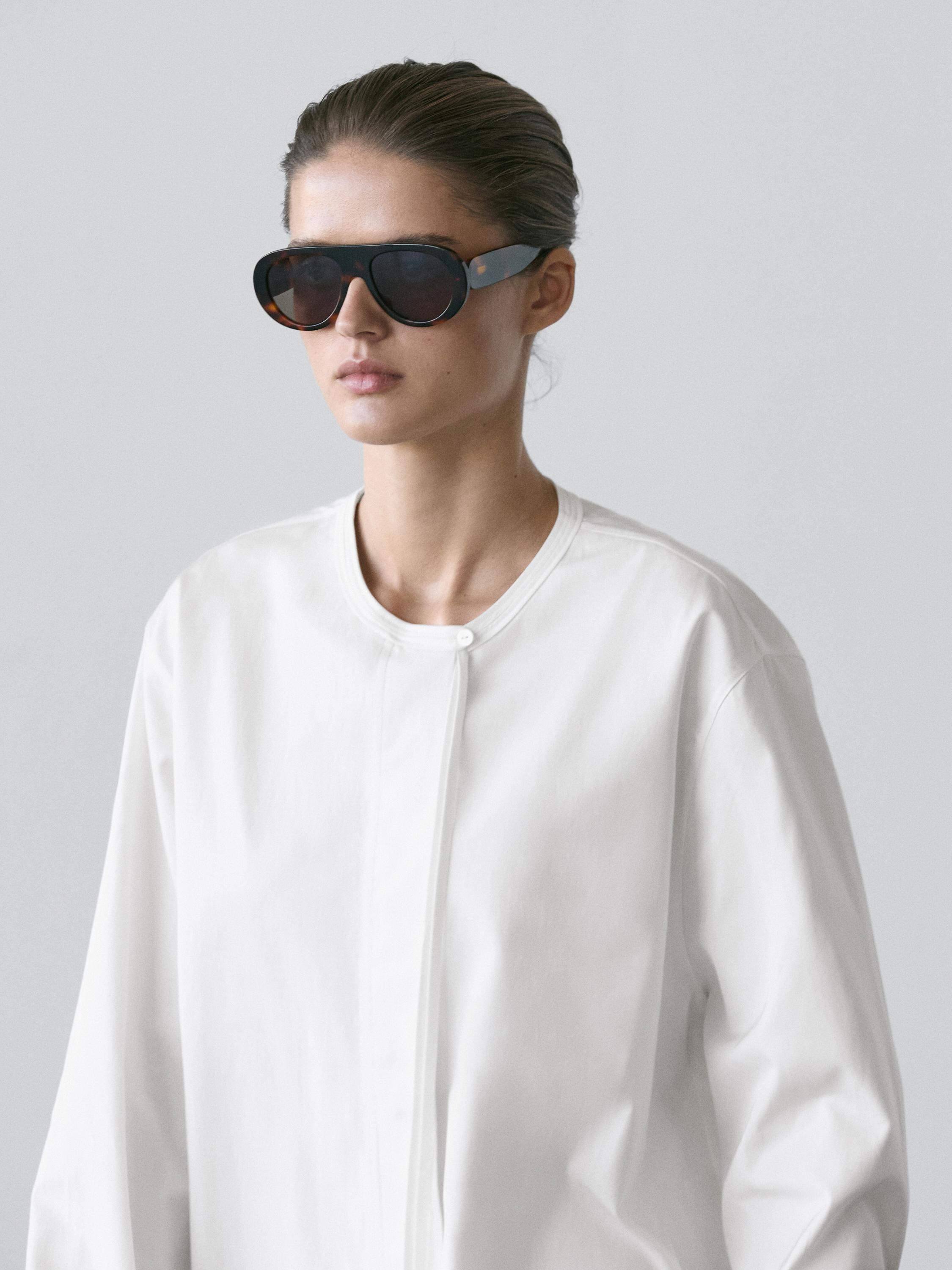 Plano moyen de chemise blanche fluide avec col rond et fermeture cachée.