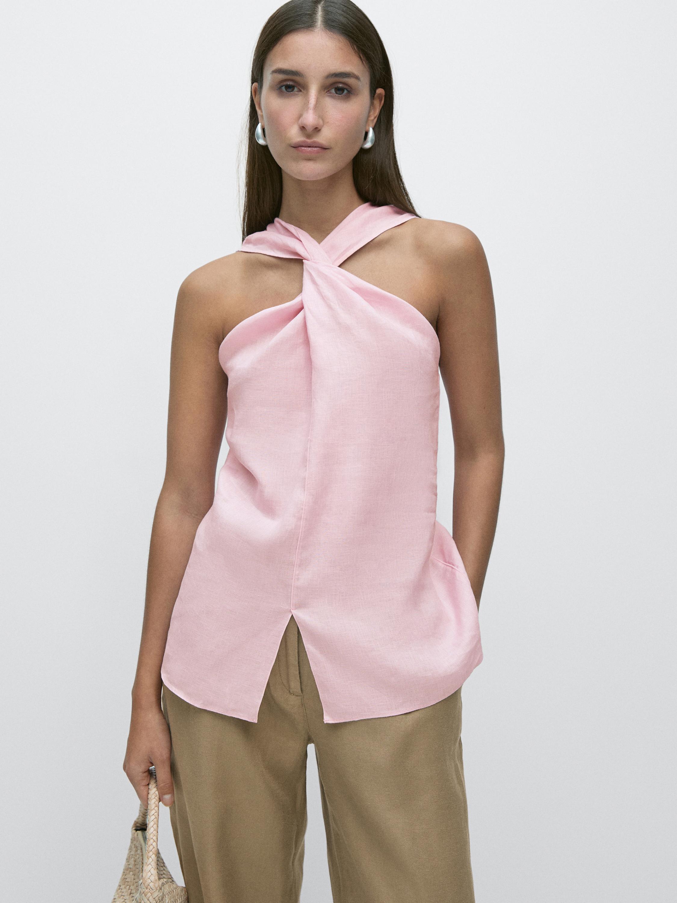 Conjunto de top rosa cruzado sin mangas con abertura frontal y pantalones beige.