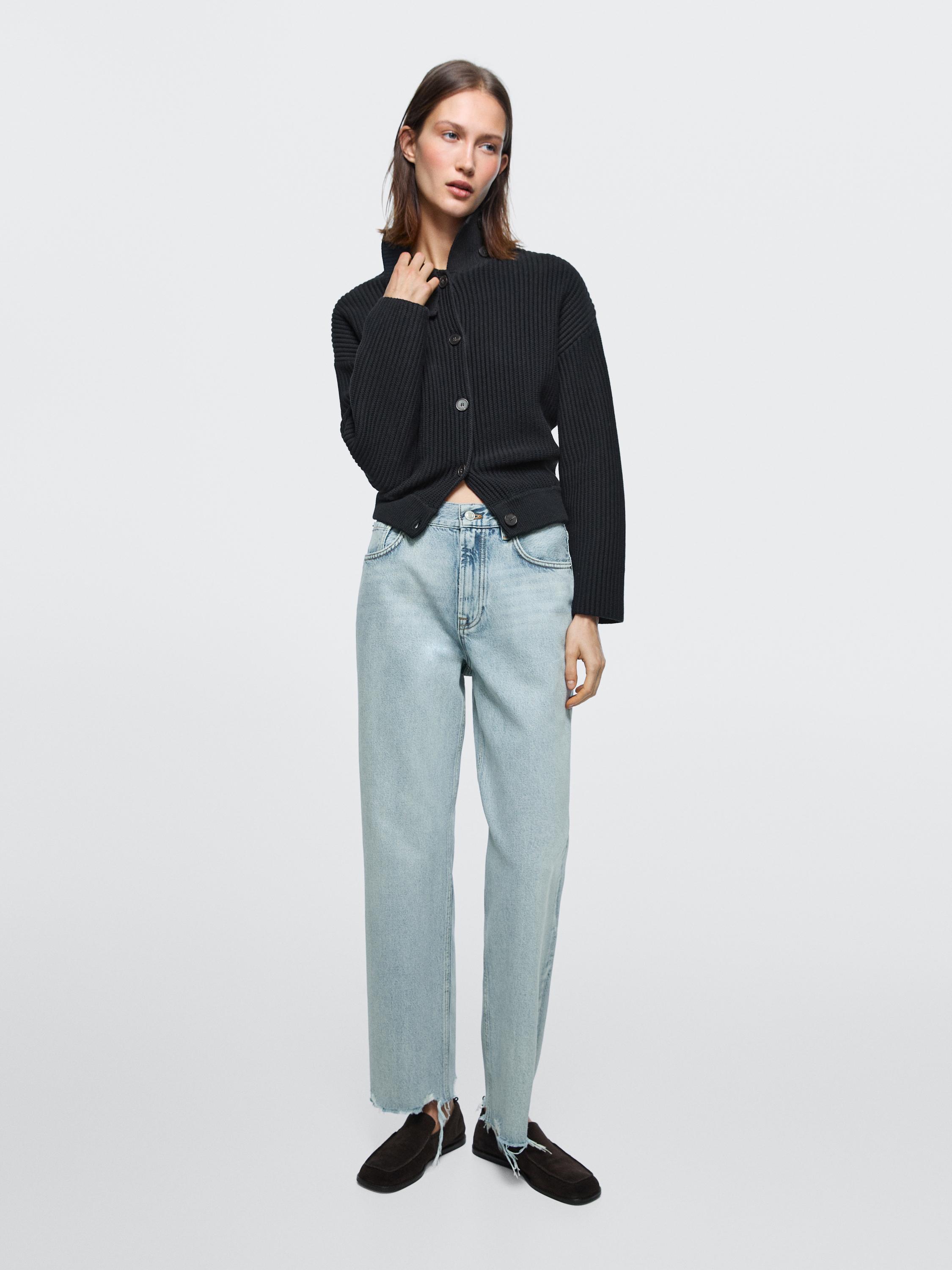 Light blue high-waisted, straight-fit jeans set with side pockets, and a black knit cardigan with buttons.