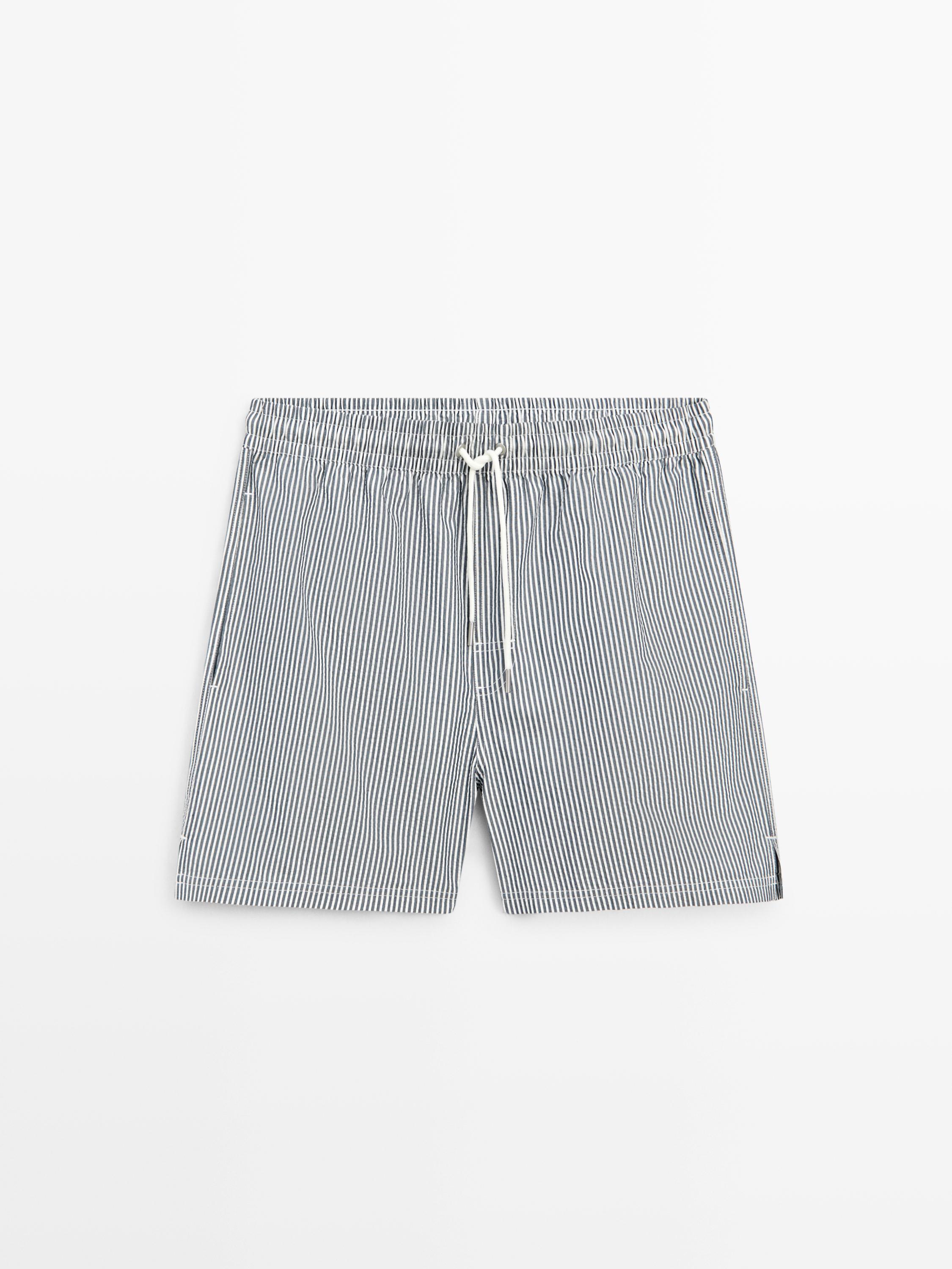 Vorderansicht von marineblauen Badeshorts mit weißen vertikalen Streifen, elastischem Bund mit Kordelzug und seitlichen Taschen.