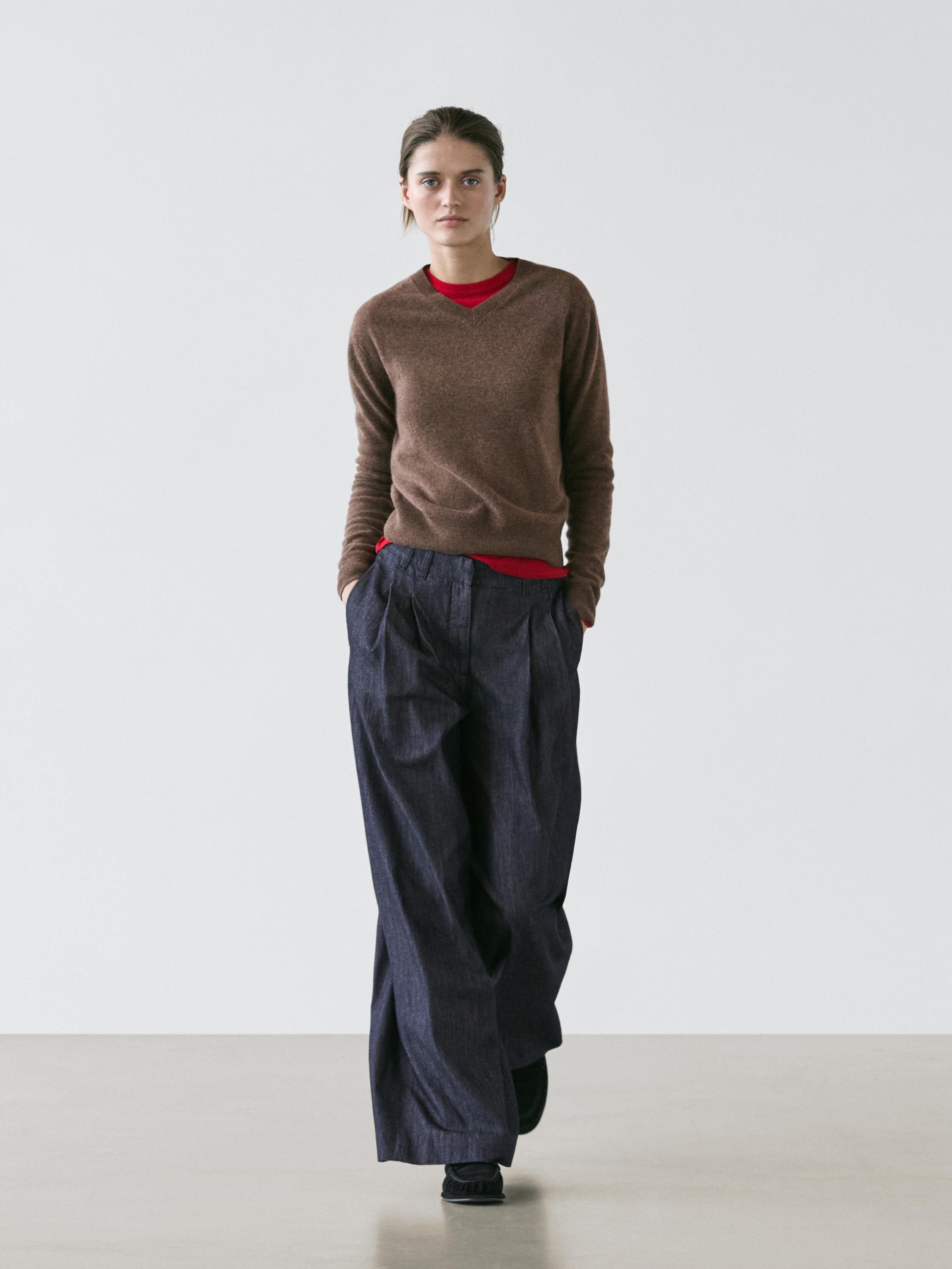 Ensemble pull marron à col en V et t-shirt rouge, jean bleu foncé large et taille haute.