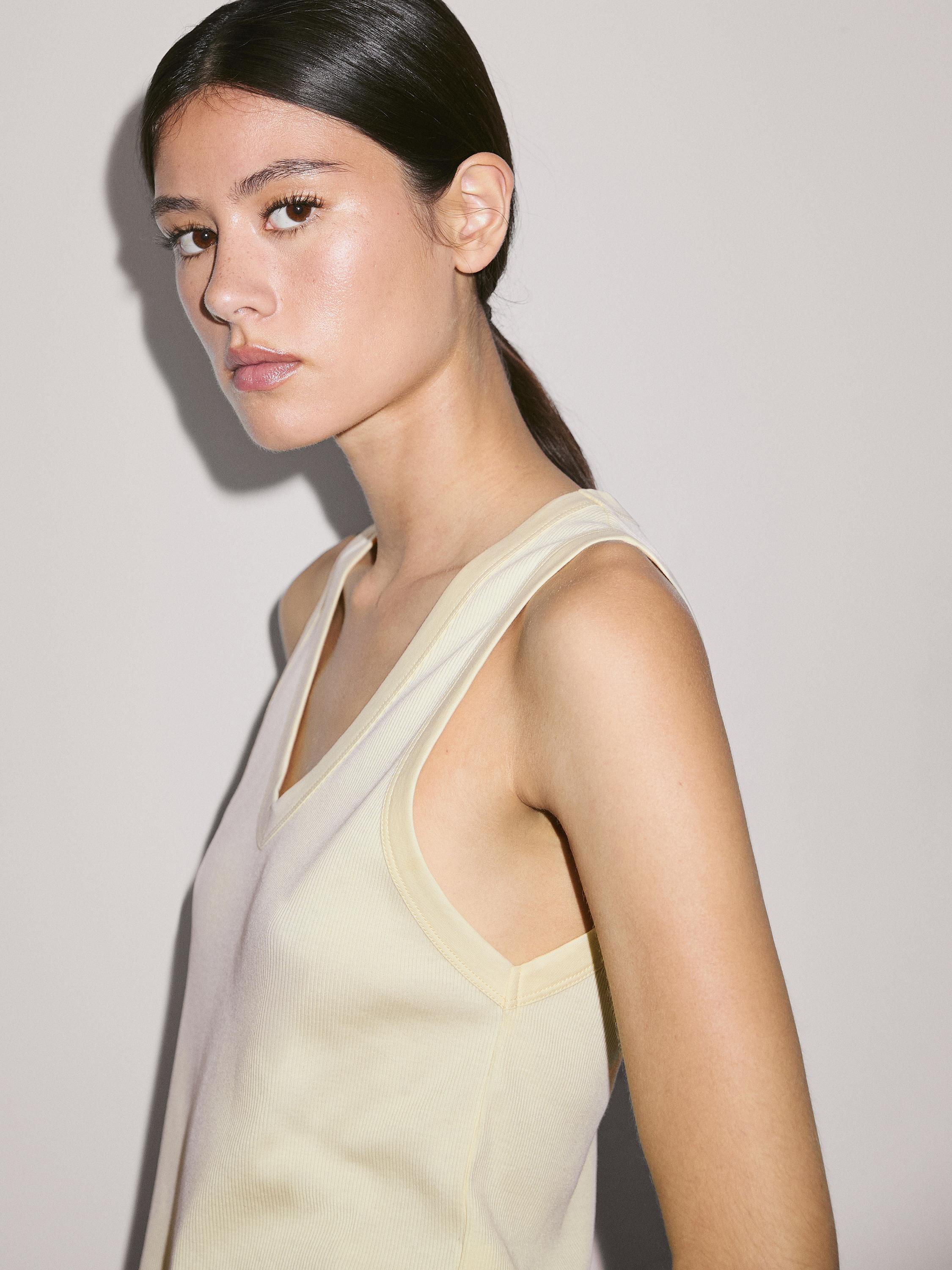 Gros plan sur un débardeur brut avec encolure en V et coutures apparentes sur les bords.