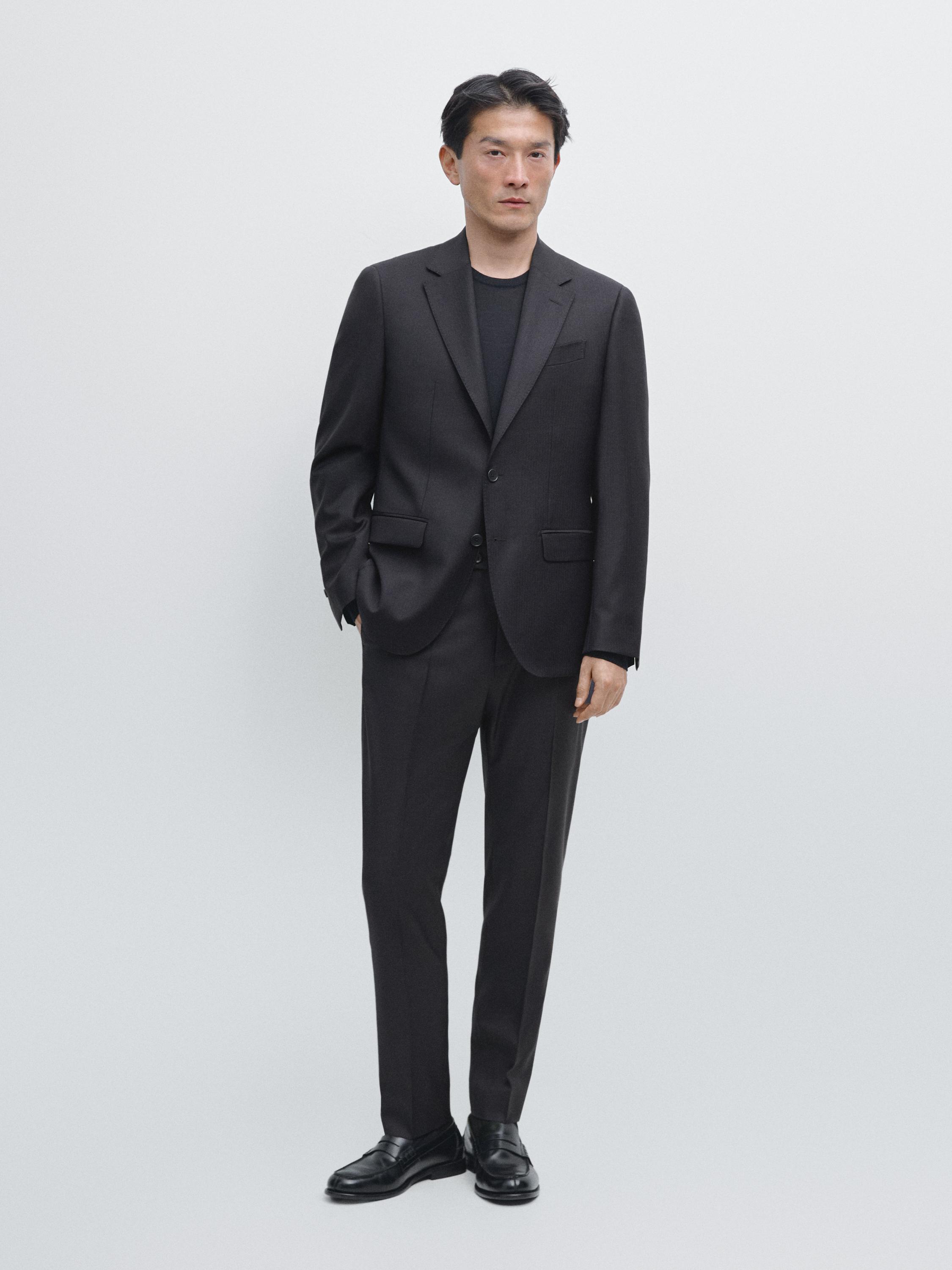 Conjunt de vestit blau marí amb americana de dos botons i butxaques amb solapa, pantaló recte i sabates negres.