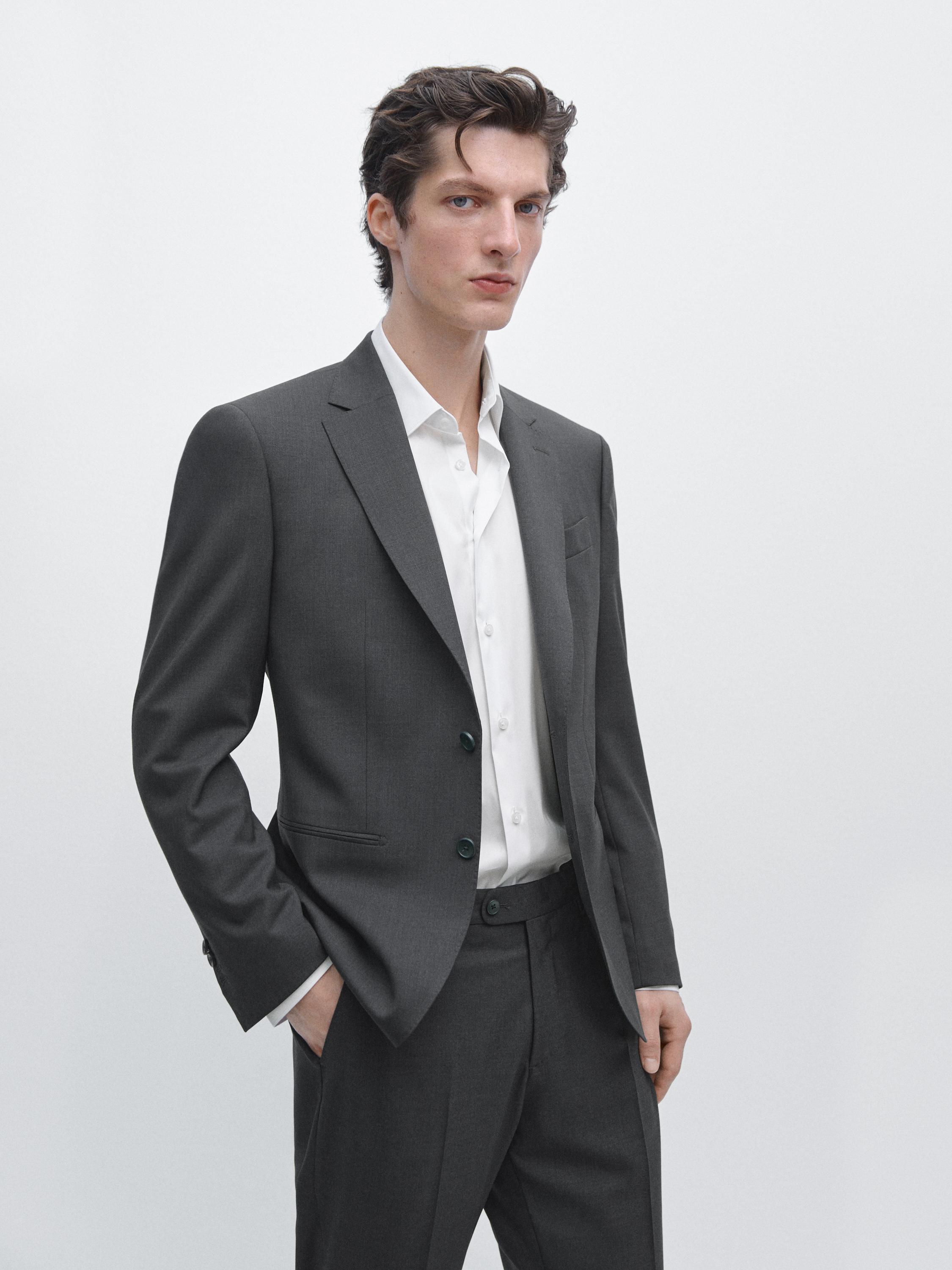 Zestaw składający się z granatowej marynarki z klapami i bocznymi kieszeniami oraz białej koszuli.