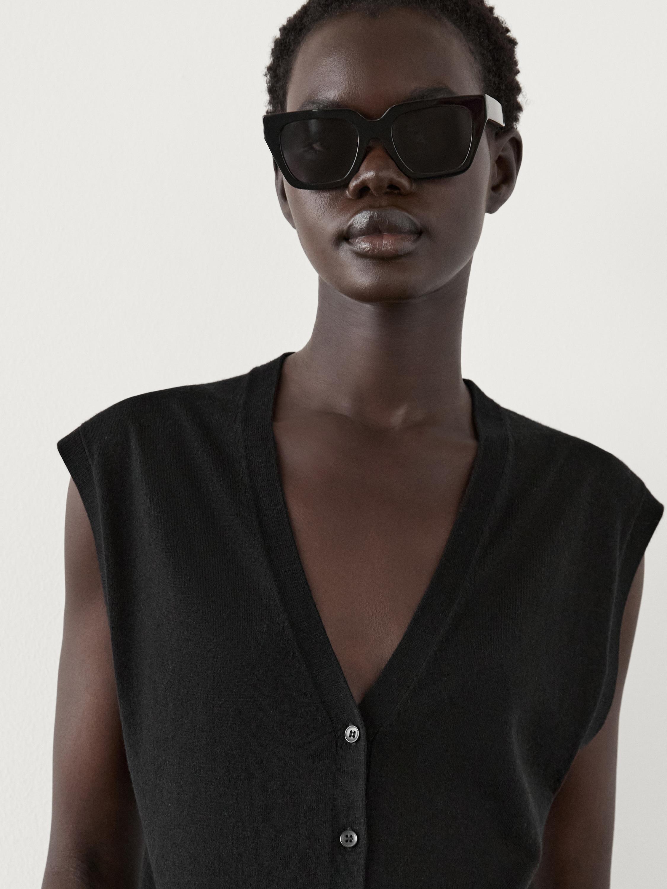 صورة مقربة لسترة سوداء بياقة على شكل V وأزرار أمامية.