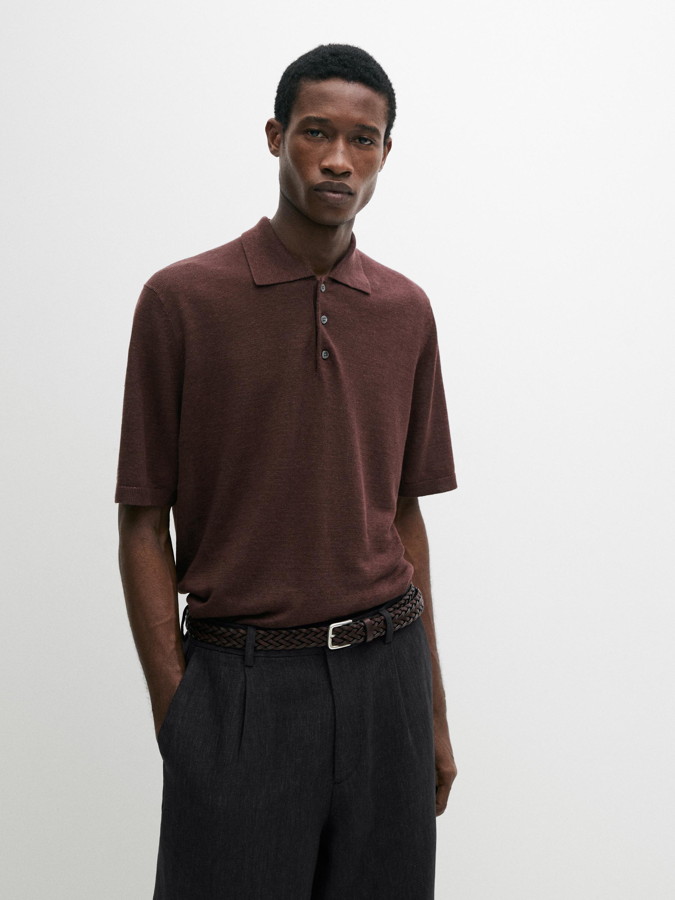 Burgunderrotes Polo-Jersey-Set mit Knöpfen und dunklen Hosen mit geflochtenem Gürtel.