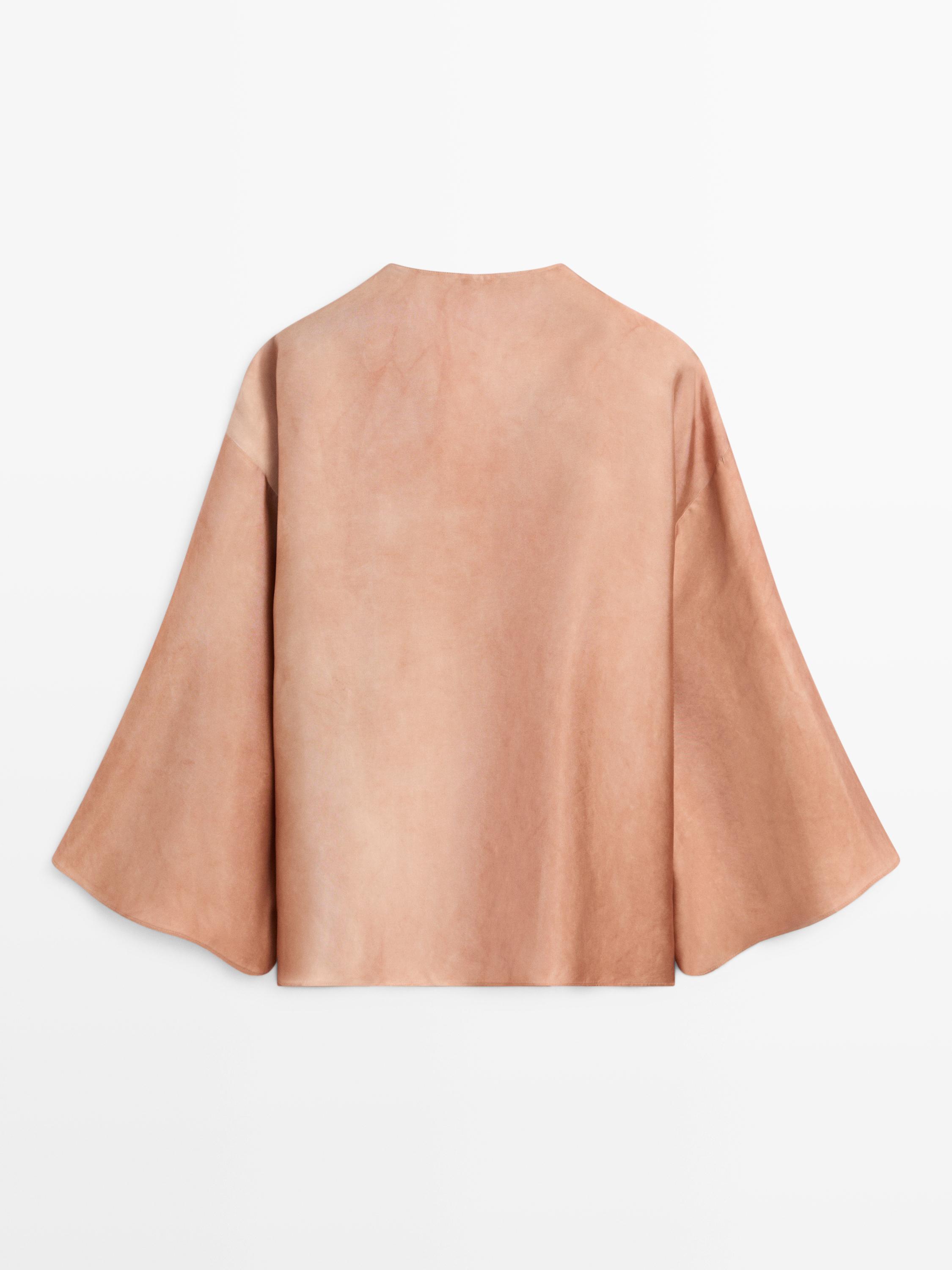 Vista posterior de camisa beixe con mangas anchas e corte recto.