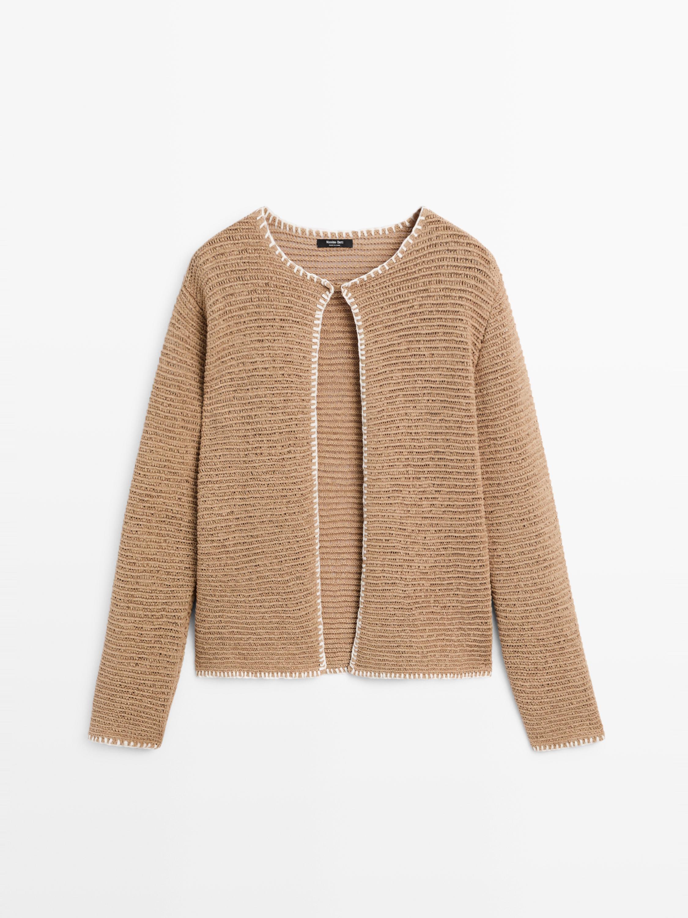 Mặt trước của áo khoác cardigan màu camel có viền trắng, tay dài và cổ tròn mở.