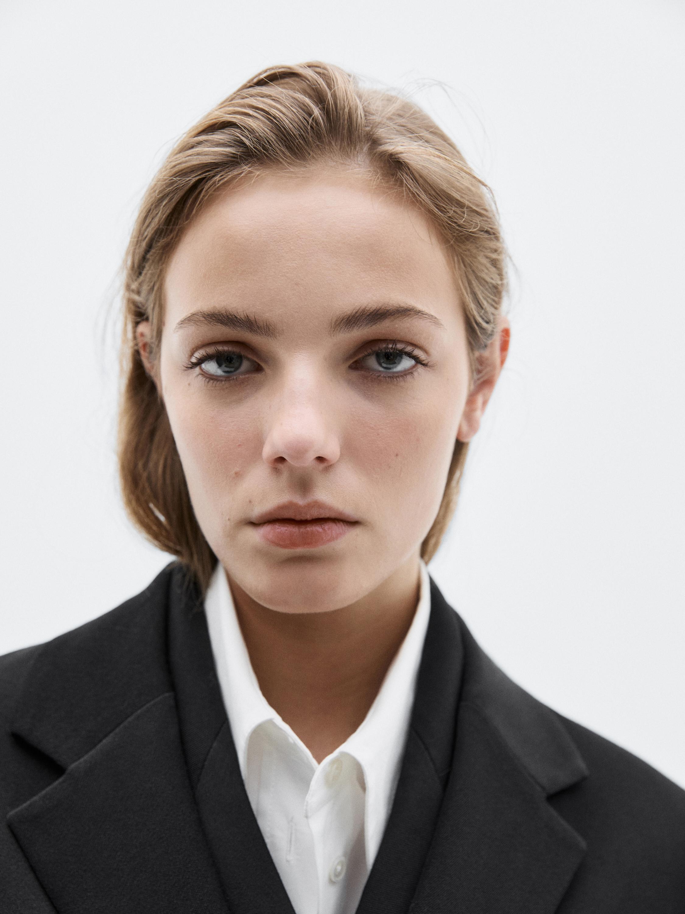 Nahaufnahme des Revers einer schwarzen Jacke über einem weißen Hemd.