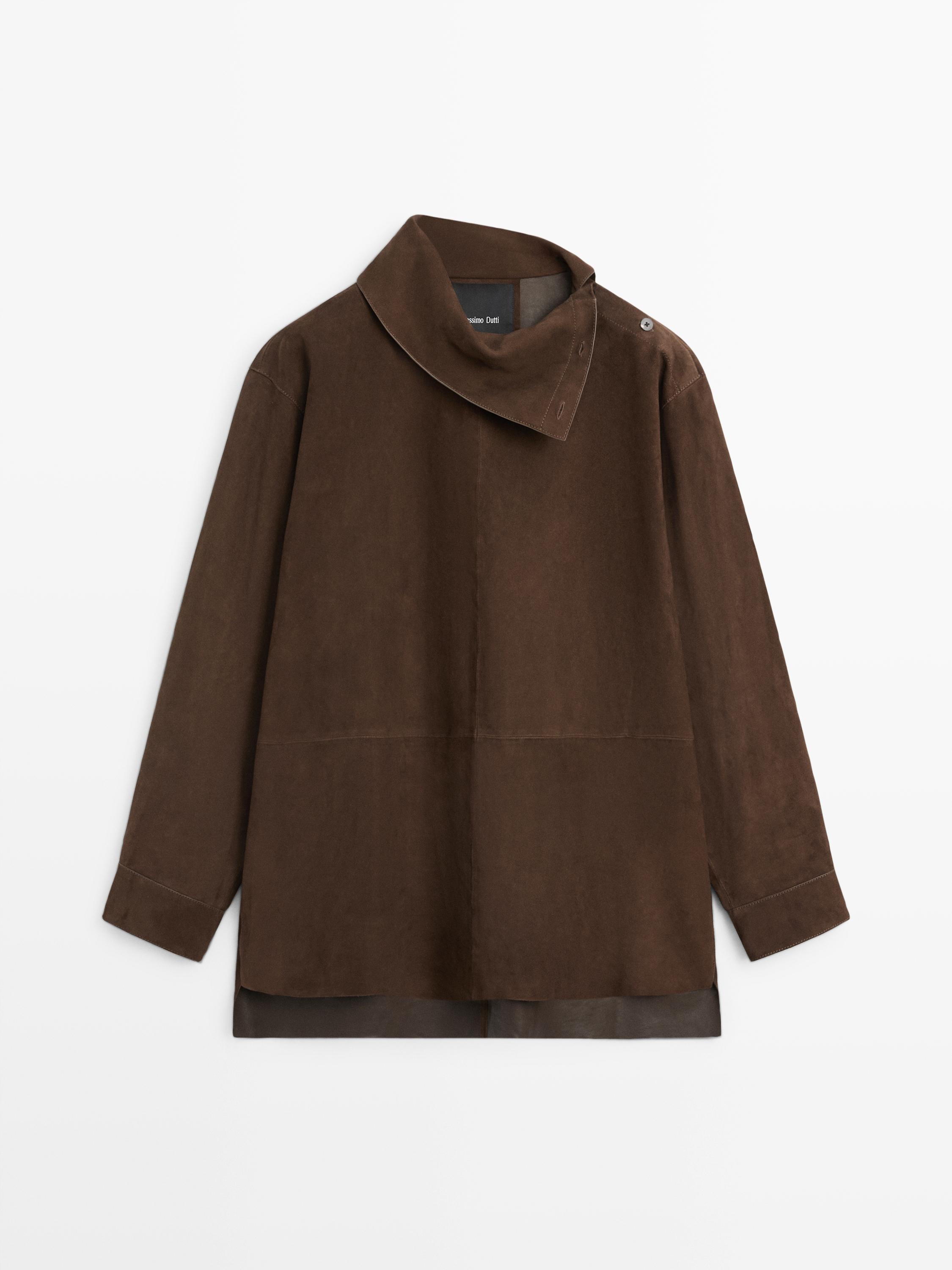 Vista frontal de blusón marrón con cuello subido y cierre de botón en el hombro. Mangas largas y corte recto.