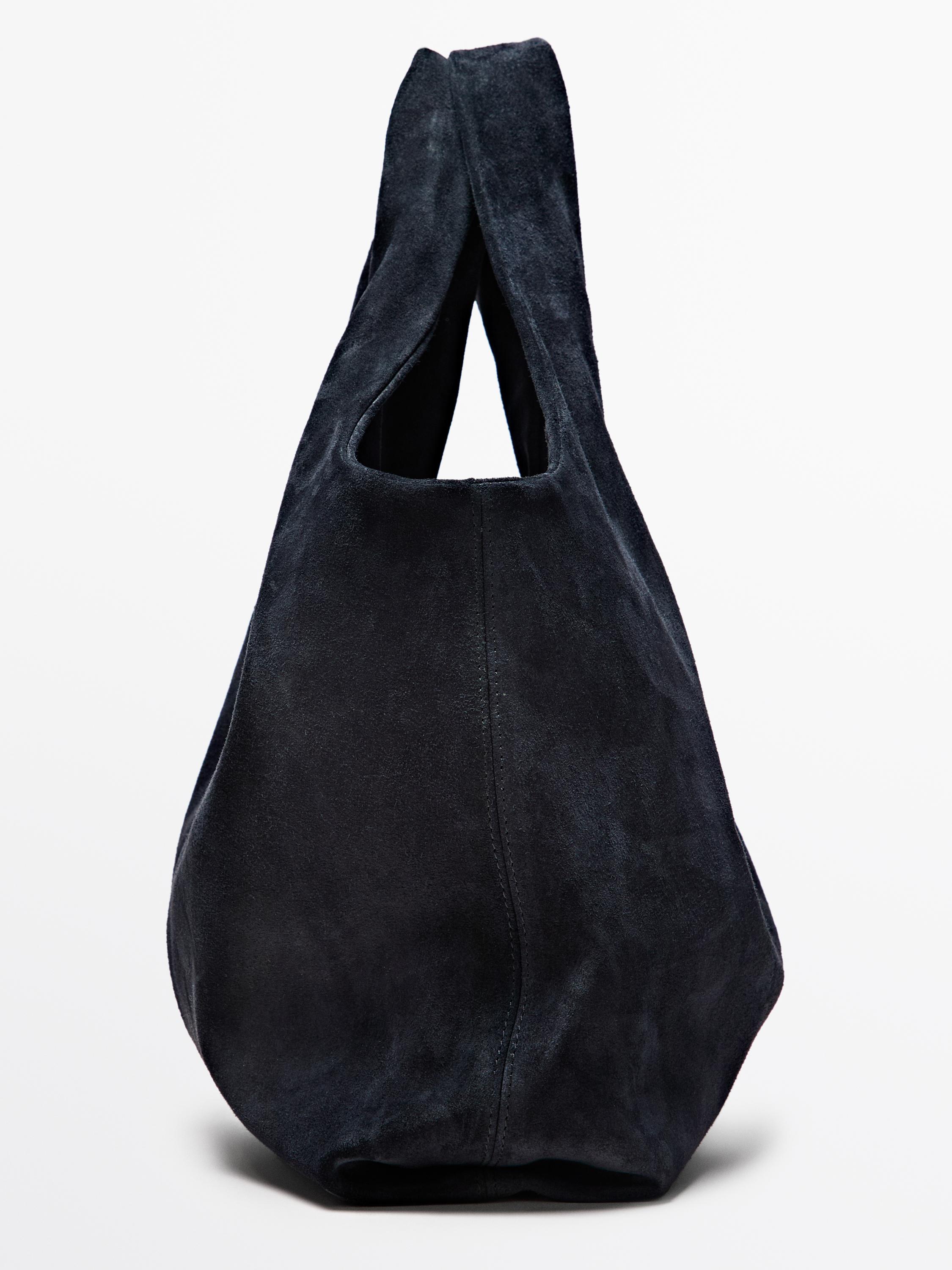 ლურჯი შოპერ ჩანთის გვერდითი ხედი ფართო სახელურებითა და დიდი დიზაინით.