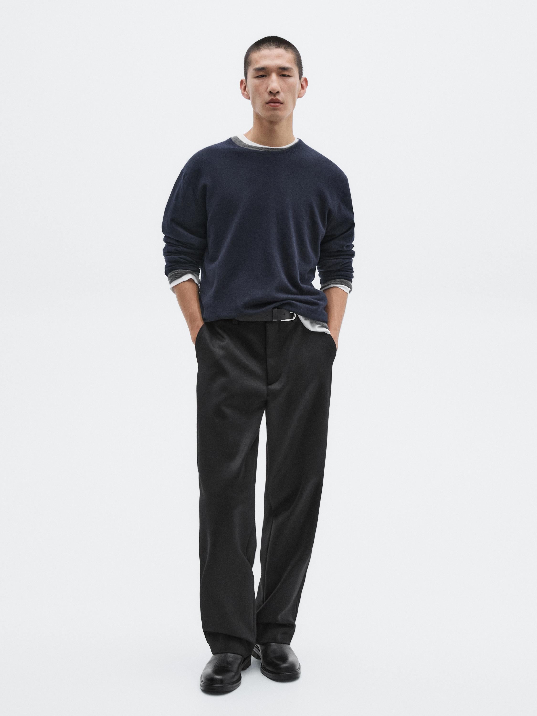 طقم سويتر كحلي بياقة دائرية وبنطلون أسود بقصة مستقيمة، مع حذاء أسود.