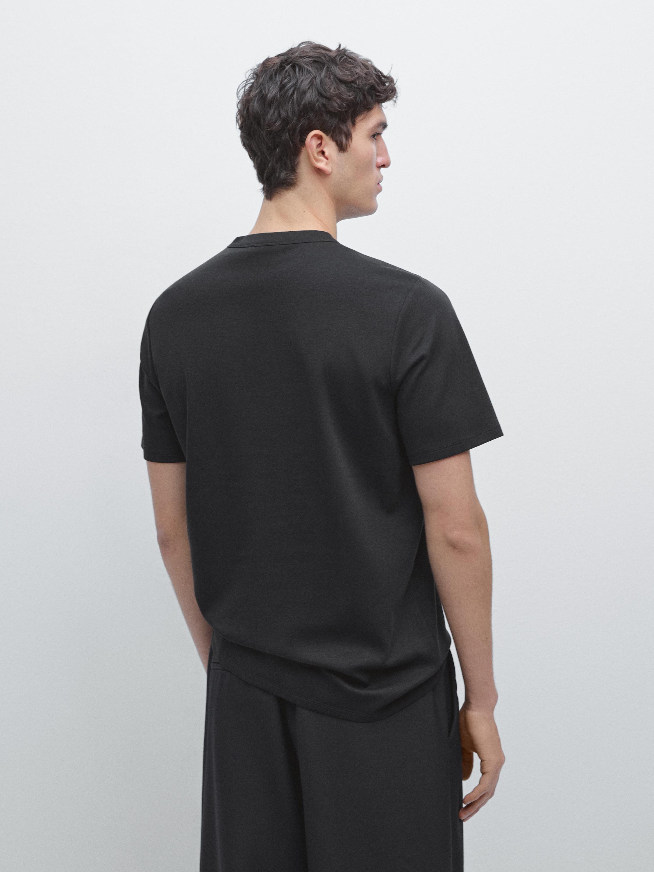 طقم تي شيرت أسود بأكمام قصيرة وبنطلون أسود، منظر خلفي.