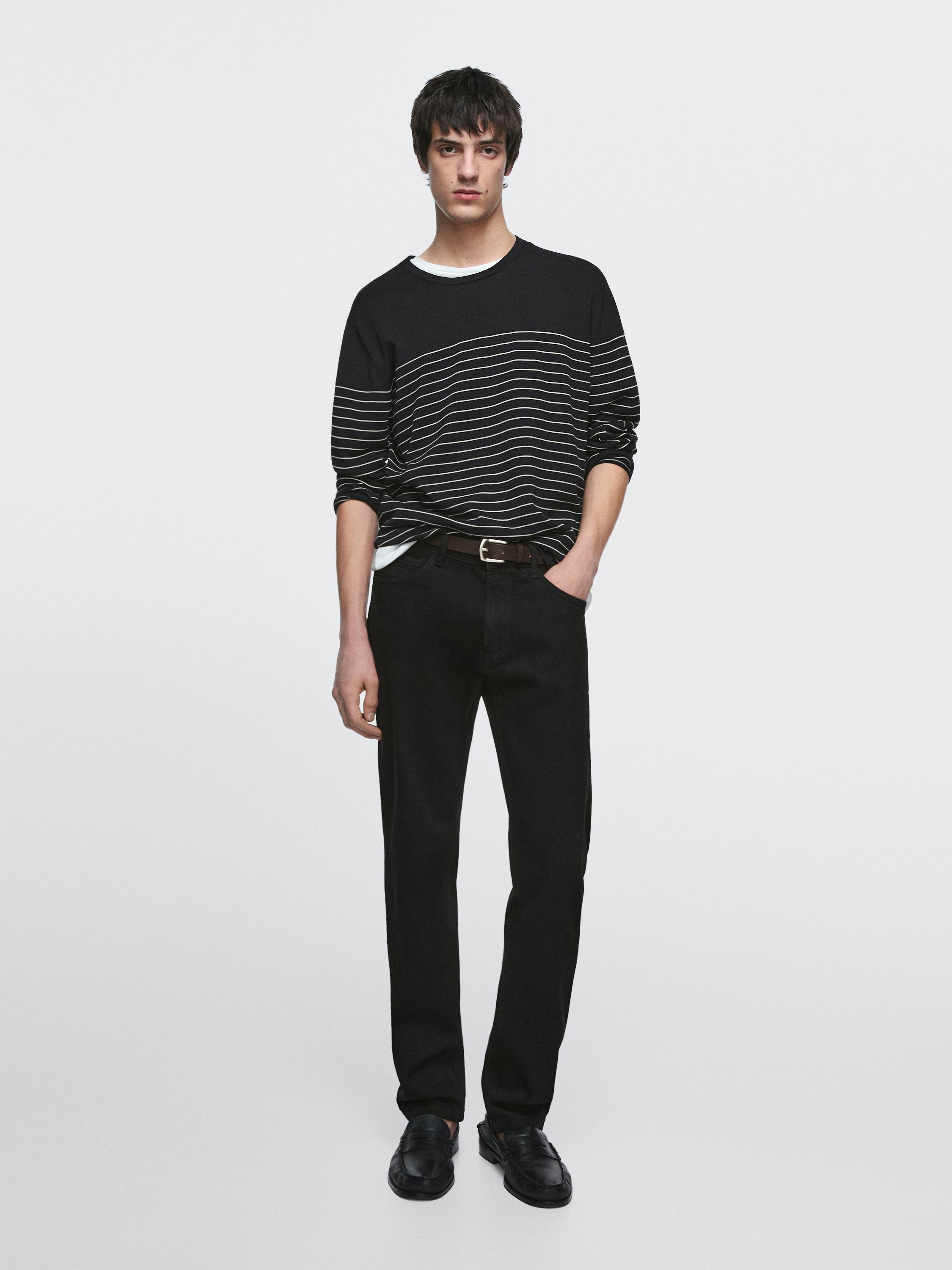 Black slim-fit jeans and black sweater with horizontal white stripes.