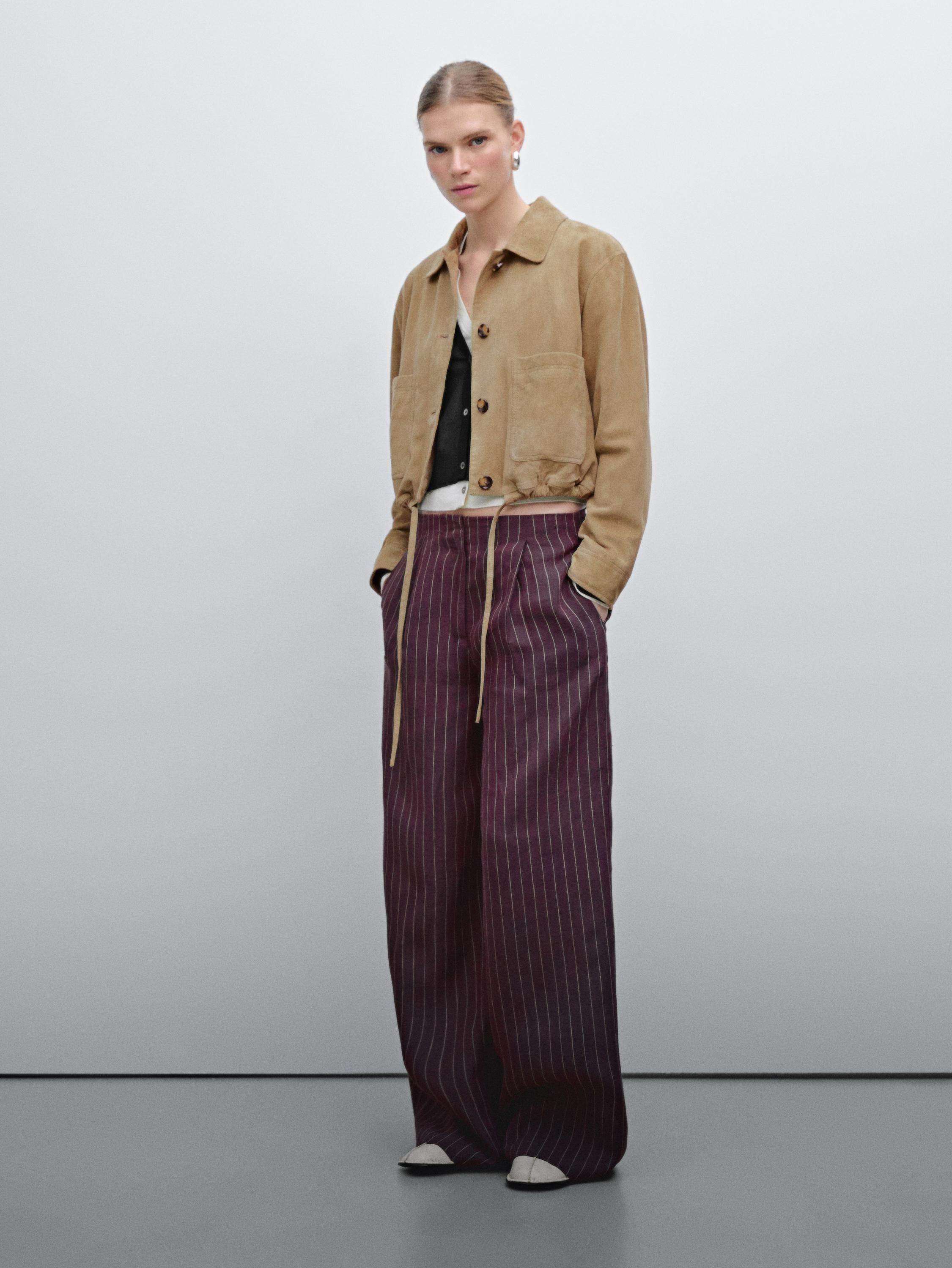 Ensemble veste beige avec poches avant et pantalon large à rayures verticales bordeaux.