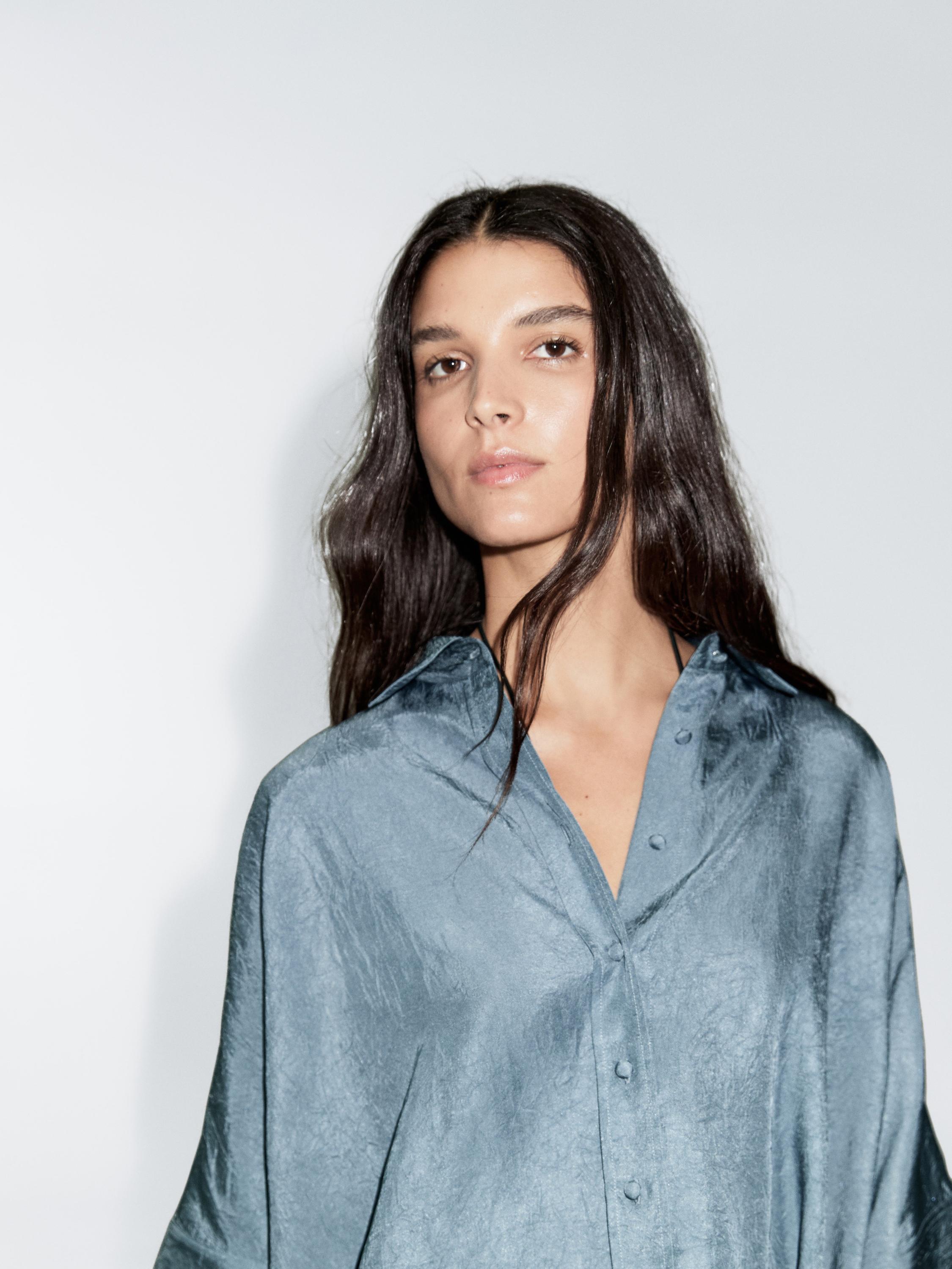 لقطة متوسطة لبلوزة زرقاء فاتحة بأزرار مغلفة ظاهرة من الأمام.