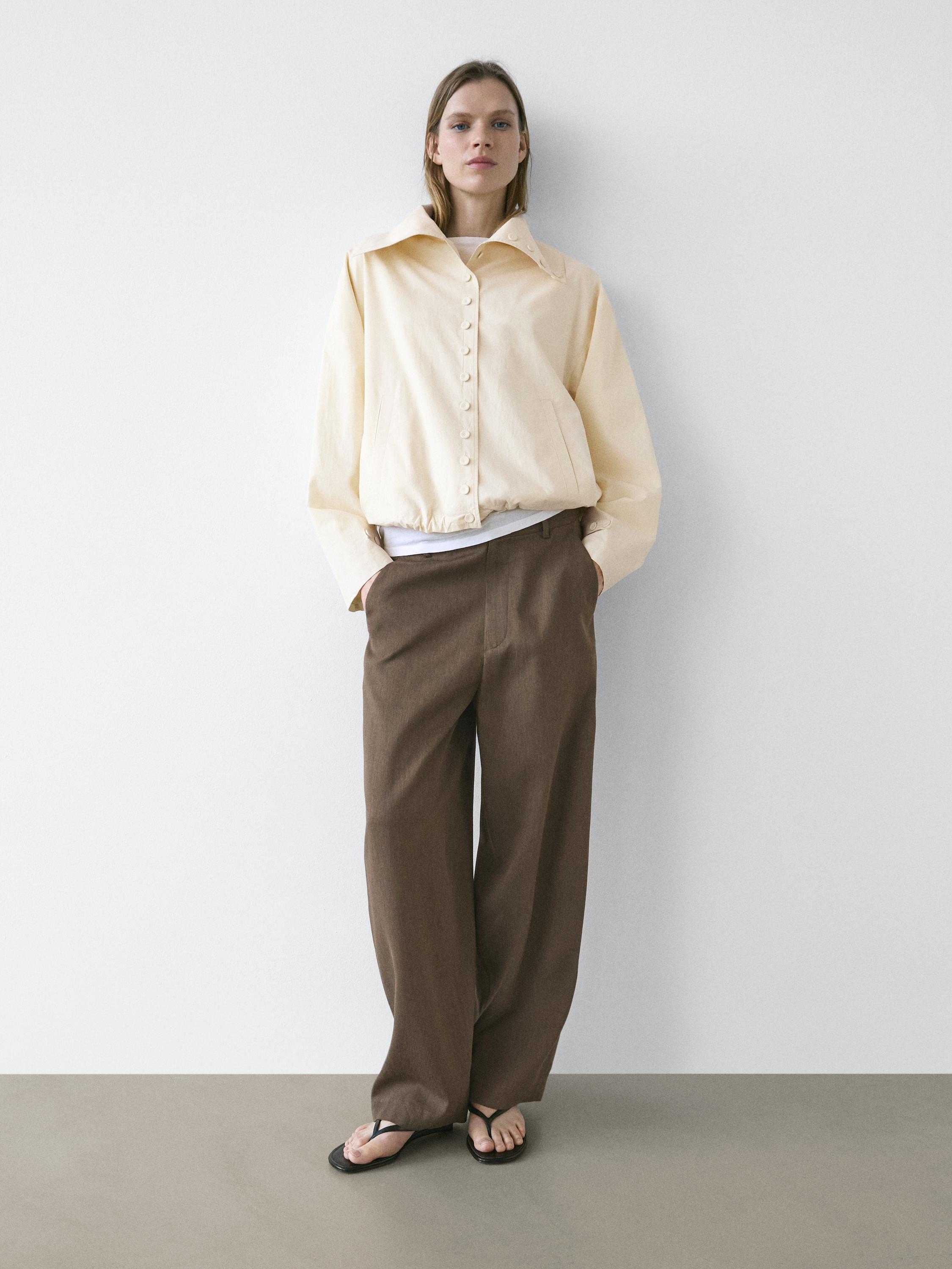 Conjunt de jaqueta beix amb botons i pantalons marrons de cama ampla amb butxaques laterals.