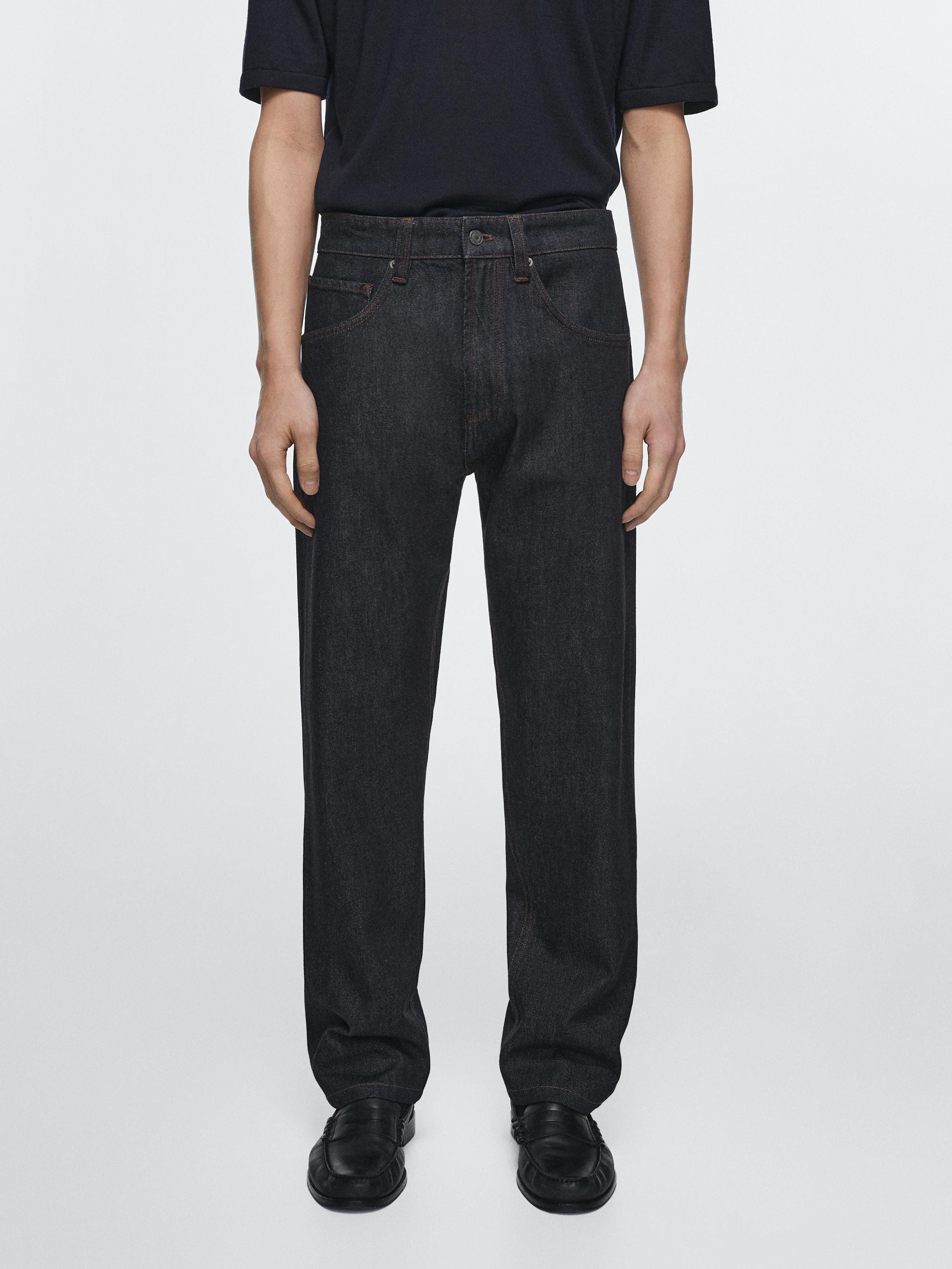 طقم بنطلون أسود بقصة مستقيمة مع جيوب أمامية وخلفية ظاهرة، وتيشيرت أسود بأكمام قصيرة.