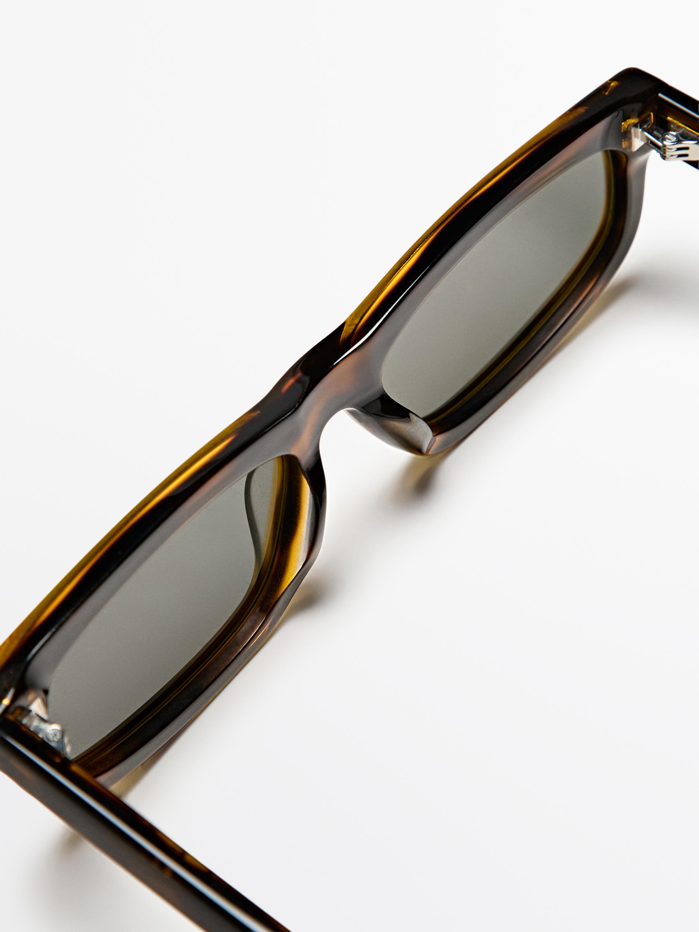 Kahverengi, kalın çerçeveli ve koyu camlı güneş gözlüğü detayı.