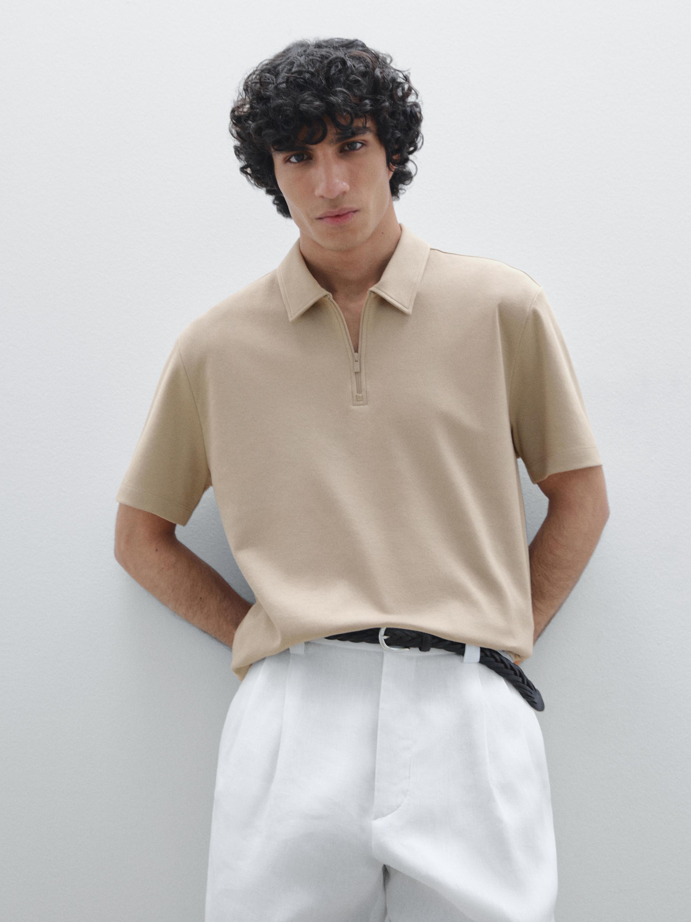 Ensemble polo beige zippé et pantalon blanc à pinces.