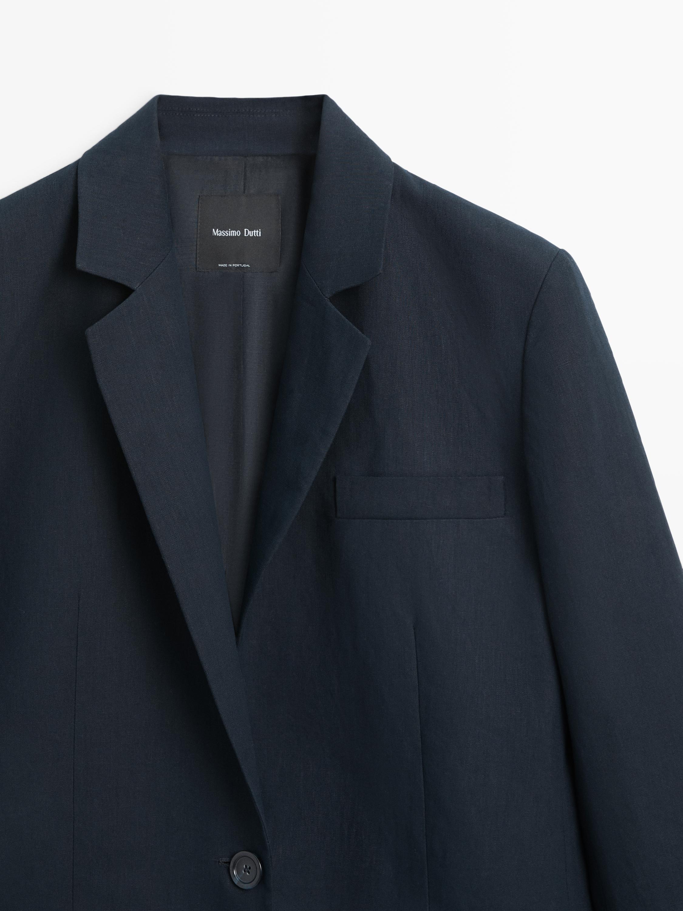 "Medium shot of a navy blue blazer with a classic lapel, upper left pocket, and visible button. Interior text: 'Massimo Dutti'."
