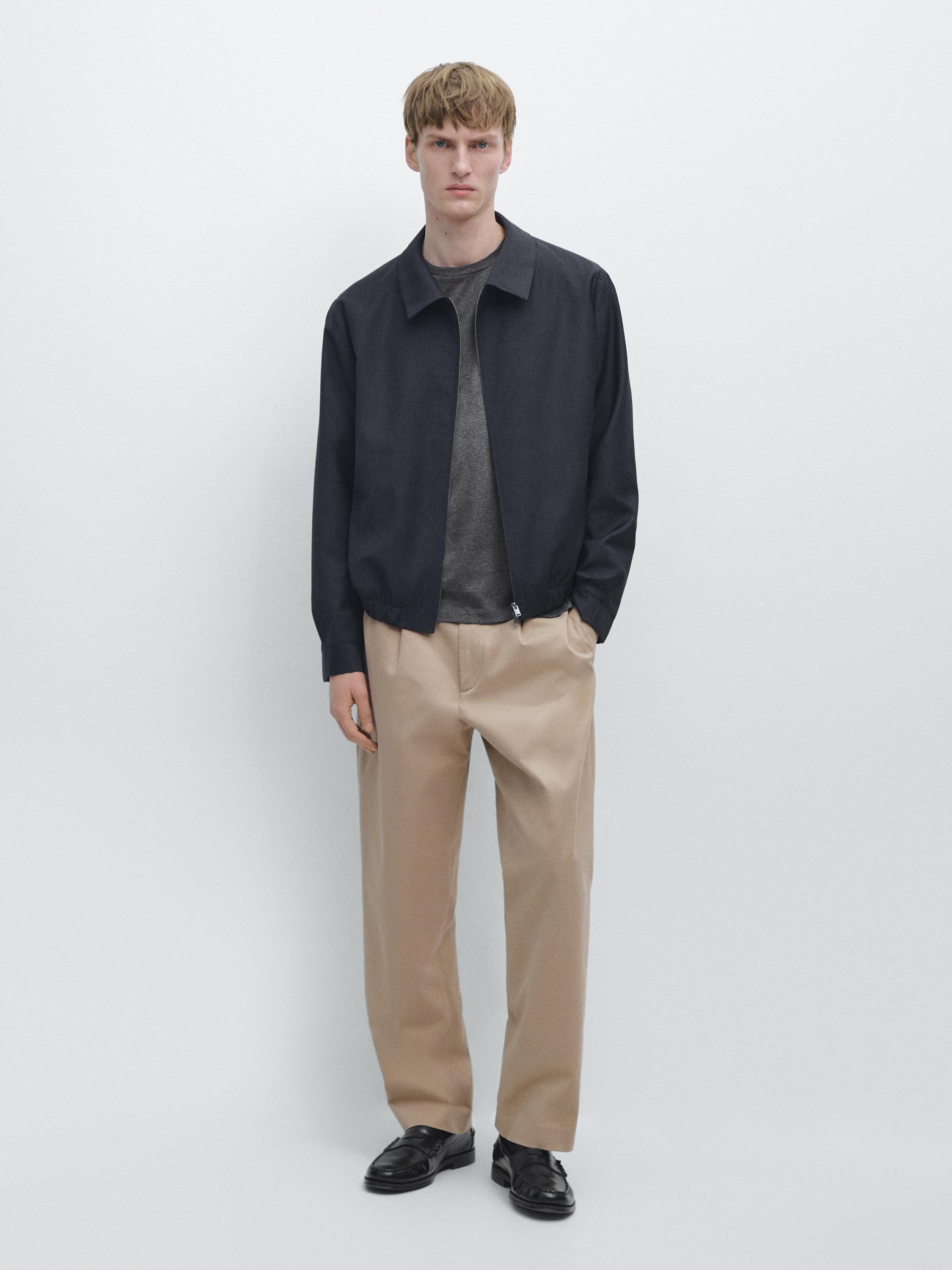 Navy blue bomber jacket, gray t-shirt, beige pants, and black loafers set.